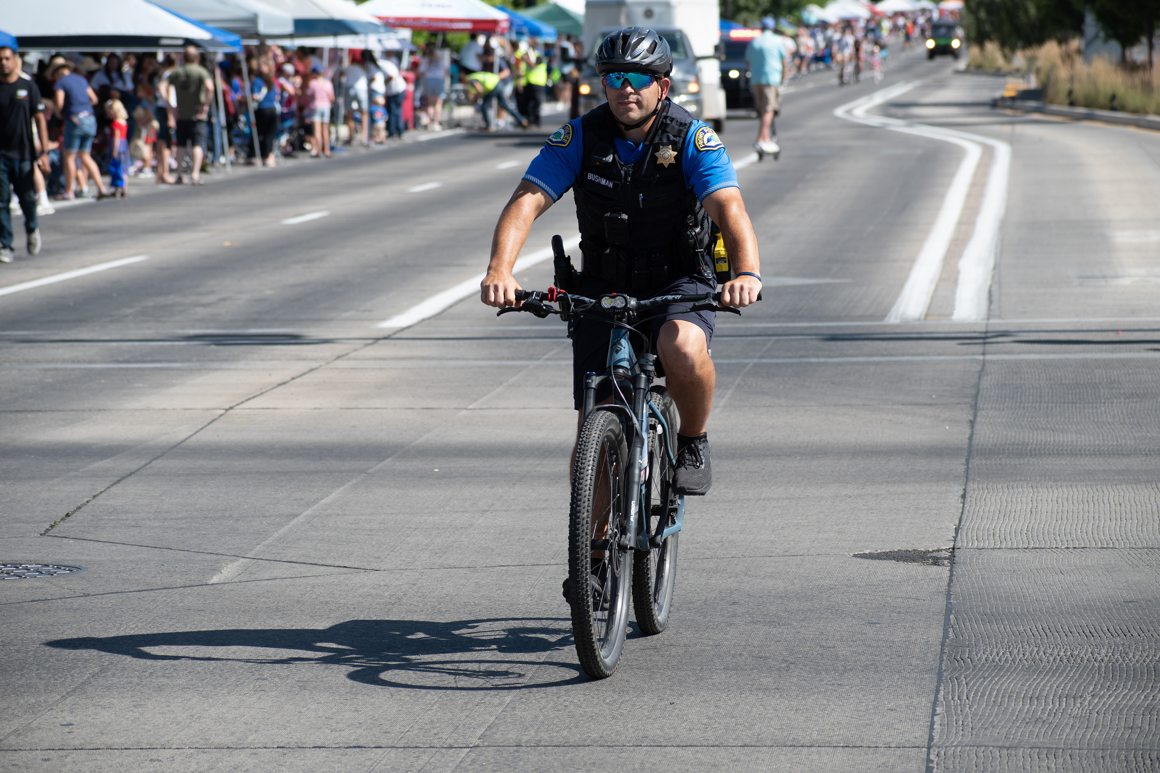 Provo, Utah – July 4, 2025: A police officer rides a bicycle along the parade route during the Freedom Festival Grand Parade, providing security and engaging with the community.