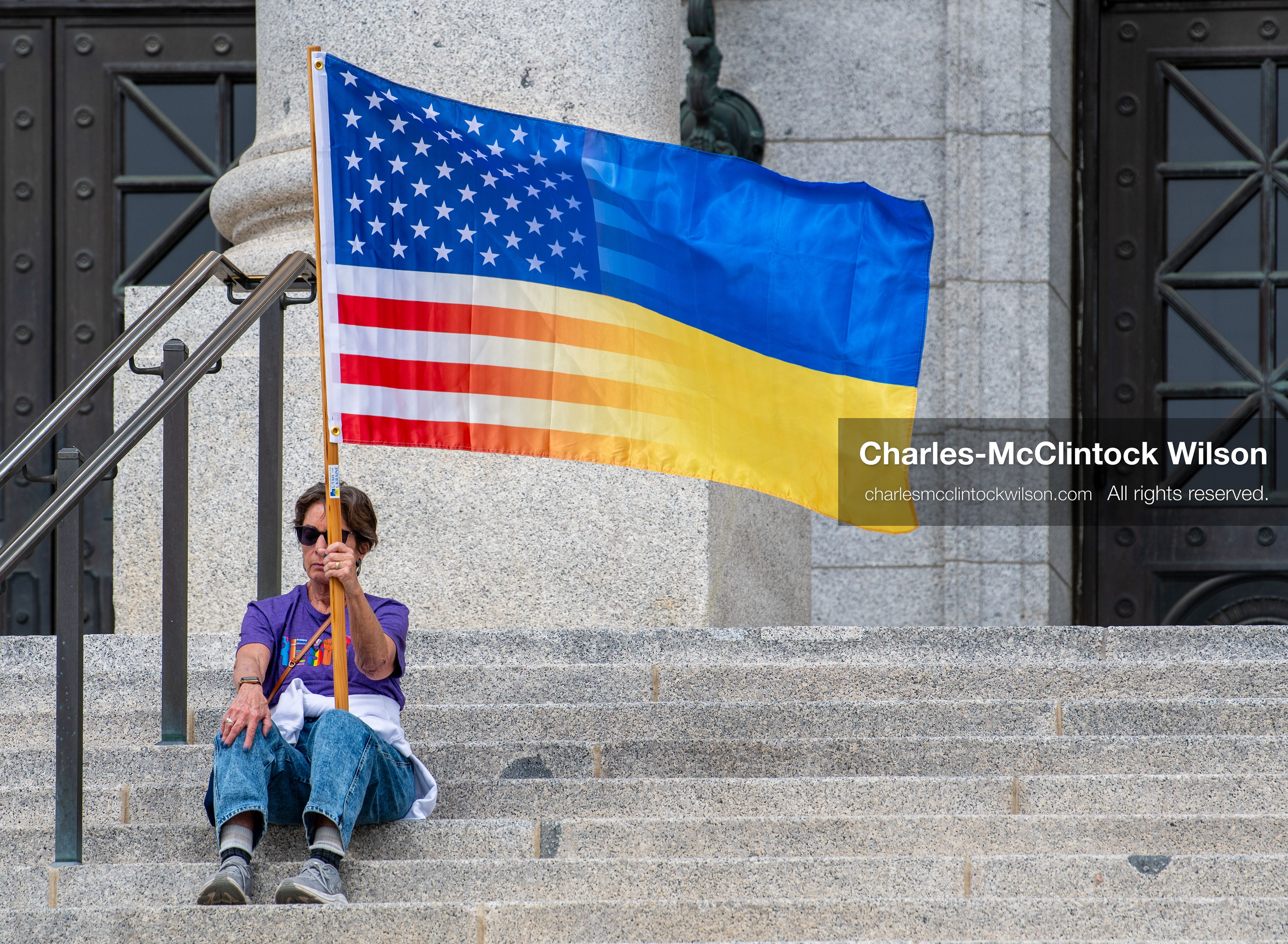 February 28, 2026, Salt Lake City, Utah, USA: A demonstrator sits on the steps near the Utah State Capitol holding a hybrid United States and Ukrainian flag during the Stand With Ukraine rally. The gathering marked the four year anniversary of the full scale Russian invasion of Ukraine and brought community members together in support of Ukrainians and local humanitarian efforts. (Credit Image: © Charles McClintock Wilson/ZUMA Press Wire)