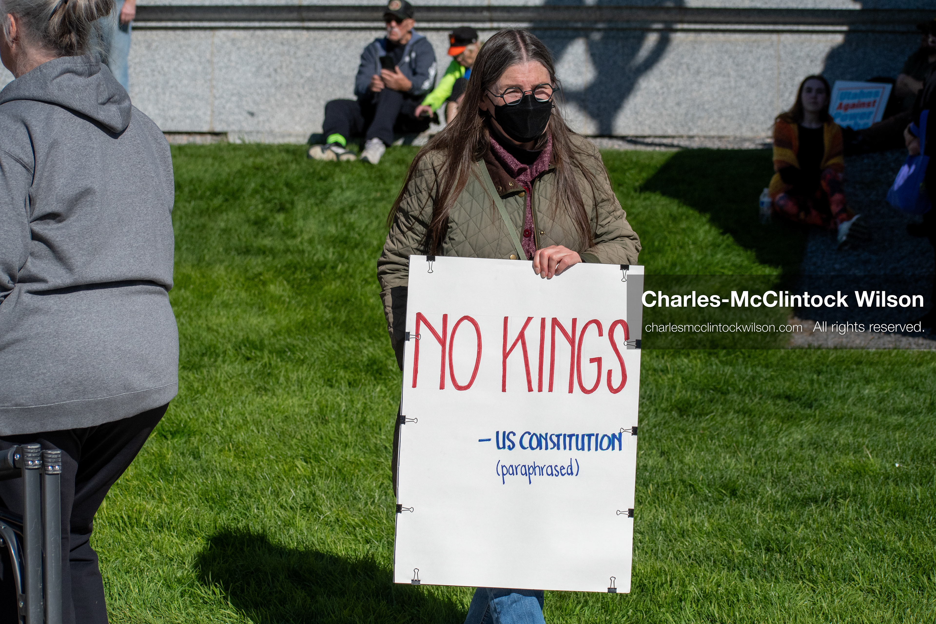 October 18, 2025, Salt Lake City, Utah, USA: A demonstrator raises a placard during a "No Kings" protest held at the Utah State Capitol. Other participants and signs are visible in the background during the public gathering.