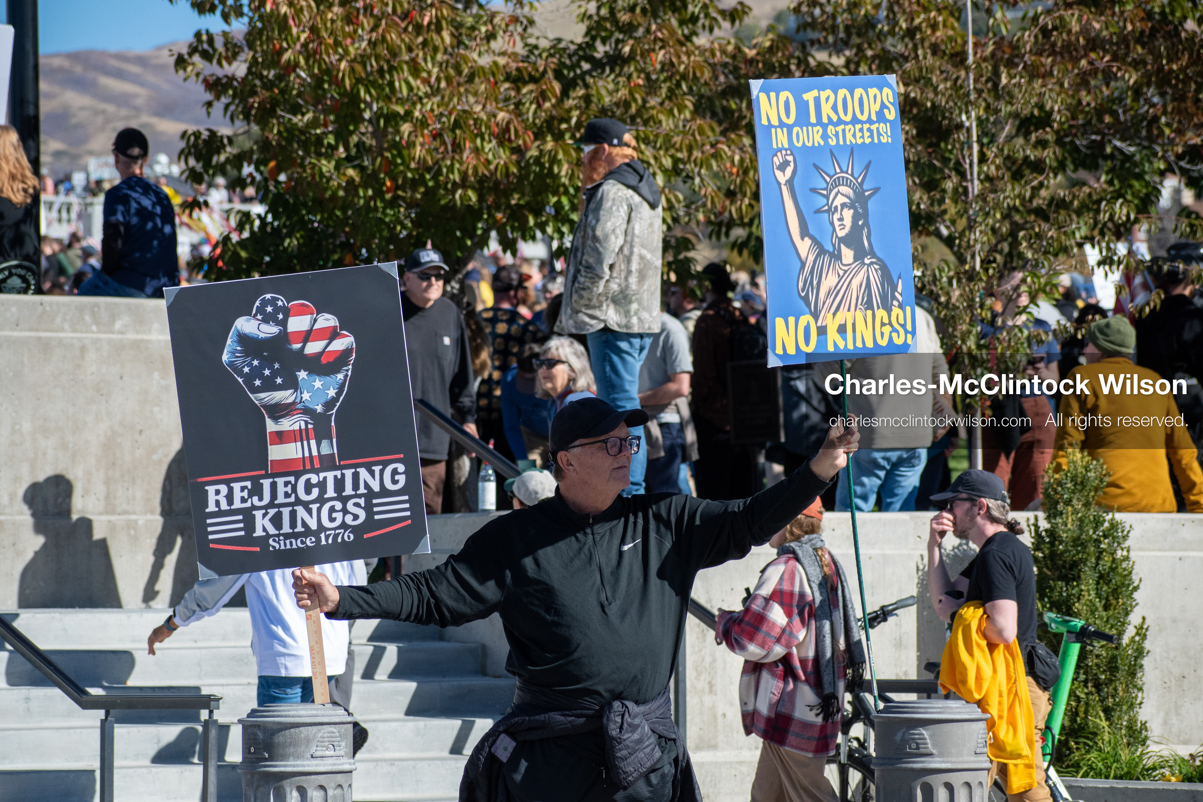 October 18, 2025, Salt Lake City, Utah, USA: A demonstrator holds signs during a "No Kings" protest at the Utah State Capitol. The protest was part of a nationwide mobilization.