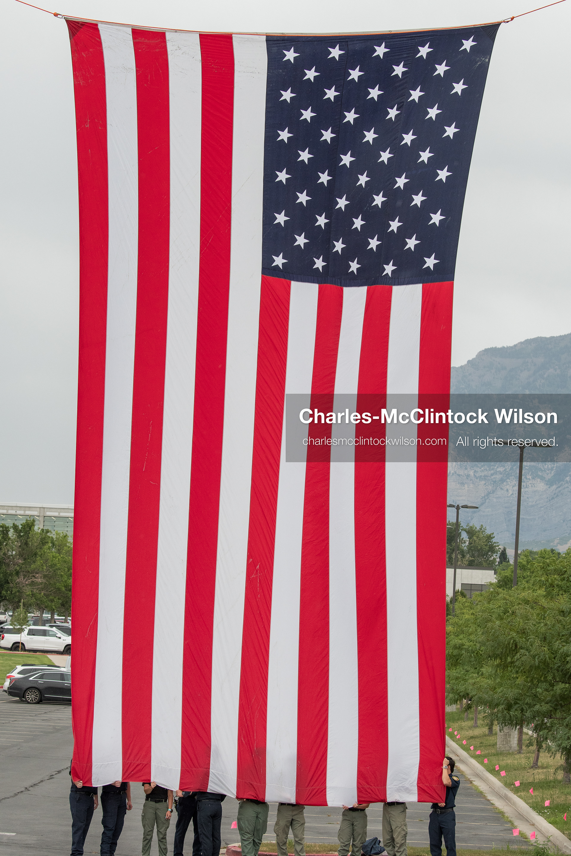 A group of first responders hangs a large American flag vertically outside the UCCU Center at Utah Valley University in Orem, Utah, on Wednesday, July 29, 2026. More than 300 people came to the public memorial ceremony to honor Provo Fire Captain Spencer Long, his wife Katrina, and three of their sons, who died after a flash flood hit their campsite near the Sunglow Campground in Wayne County. (Photo by Charles-McClintock Wilson/Sipa USA)
