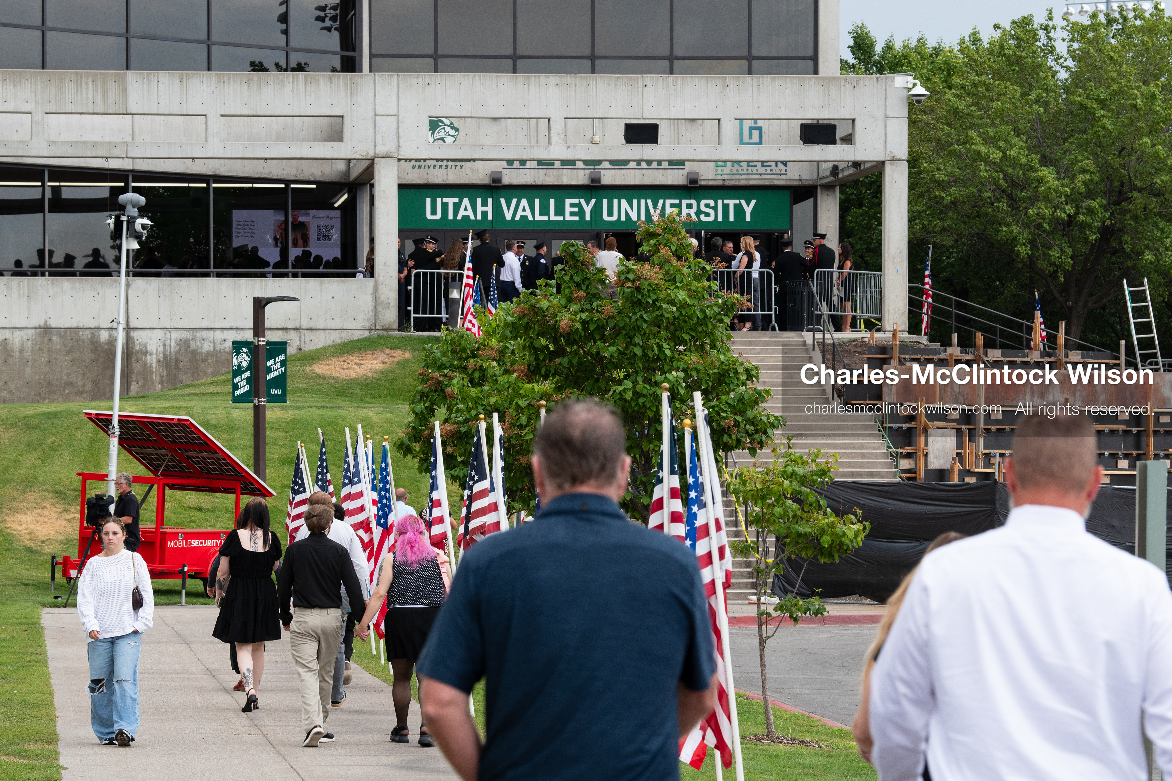 Attendees walk along a sidewalk lined with American flags toward the entrance of the UCCU Center on the campus of Utah Valley University in Orem, Utah, on Wednesday, July 29, 2026. More than 300 people came to the public memorial ceremony to honor Provo Fire Captain Spencer Long, his wife Katrina, and three of their sons, who died after a flash flood hit their campsite near the Sunglow Campground in Wayne County. (Photo by Charles-McClintock Wilson/Sipa USA)