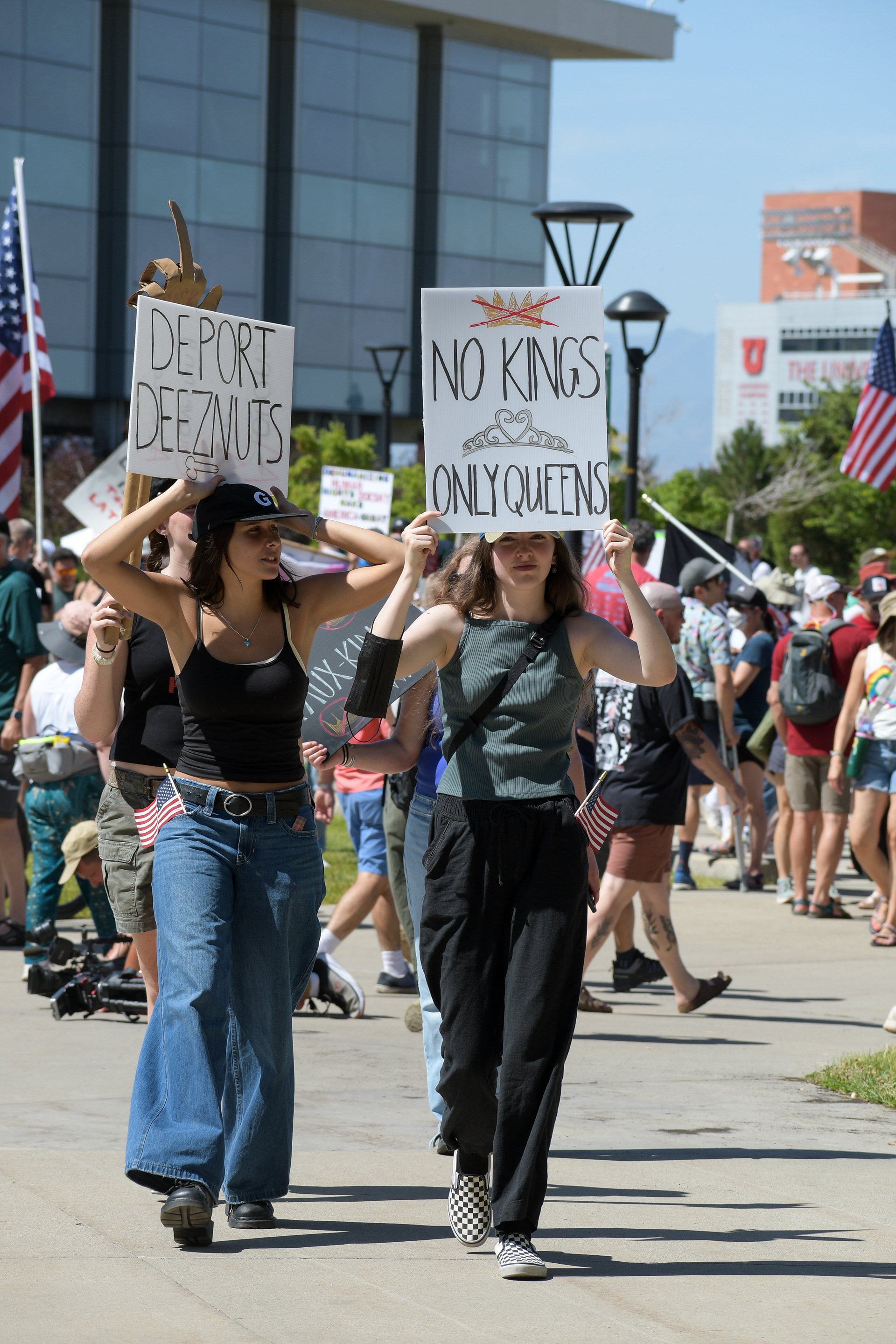 SALT LAKE CITY, UT - JUNE 14: Protesters carry signs reading “DEPORT DEEZNUTS” and “NO KINGS ONLY QUEENS” during the No Kings protest at the University of Utah on June 14, 2025, in Salt Lake City, Utah. Demonstrators gathered to denounce authoritarianism and express opposition to political figures viewed as aspiring monarchs.