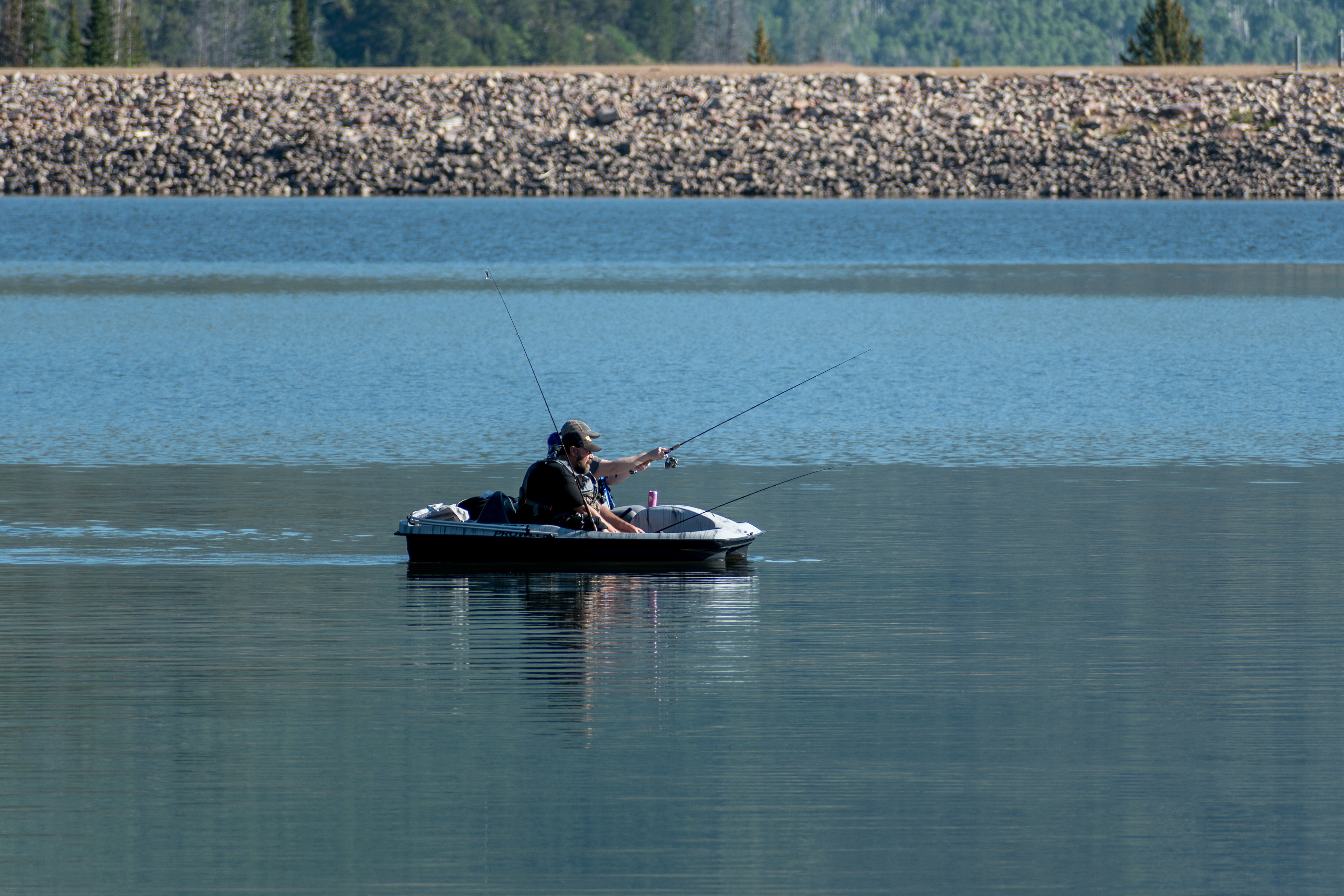 Summit County, Utah – July 20, 2025: People fish from a pedal boat on the calm waters of Smith and Morehouse Reservoir during a summer outing.