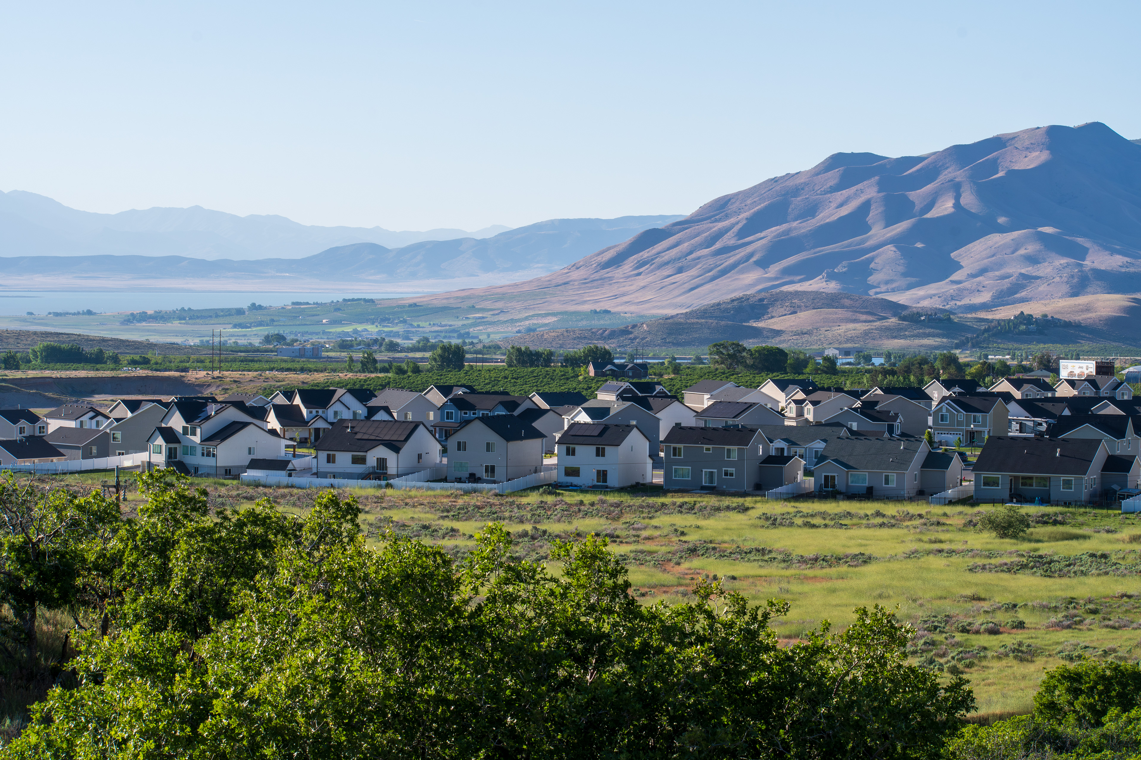 Santaquin, Utah – June 2, 2025: Wide view of a residential neighborhood with a mountainous backdrop and open valley under a clear sky.