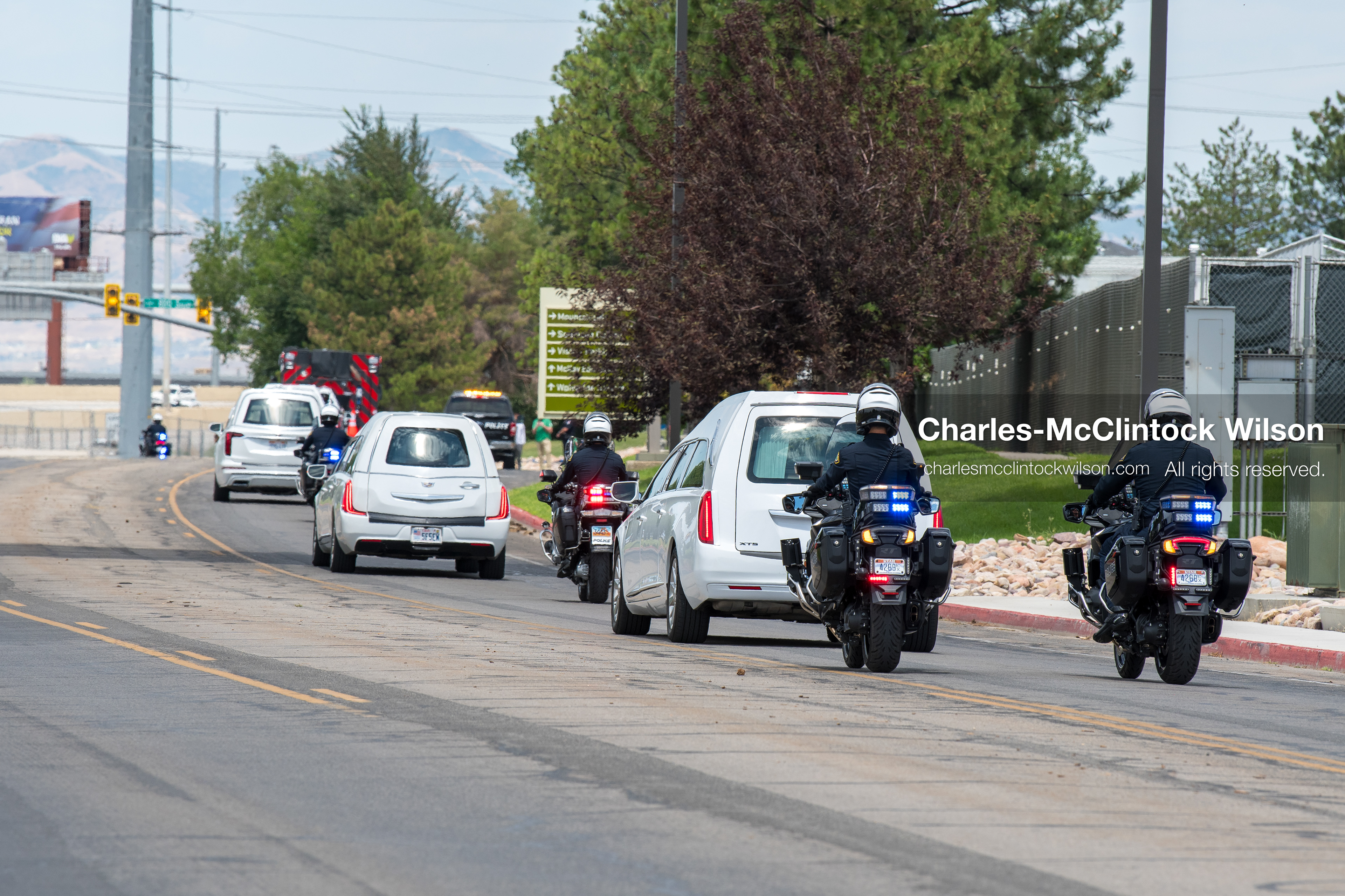 A police motorcycle escort leads a motorcade of white hearses along a public roadway outside the UCCU Center at Utah Valley University in Orem, Utah, on Wednesday, July 29, 2026. More than 300 people came to the public memorial ceremony to honor Provo Fire Captain Spencer Long, his wife Katrina, and three of their sons, who died after a flash flood hit their campsite near the Sunglow Campground in Wayne County. (Photo by Charles-McClintock Wilson/Sipa USA)