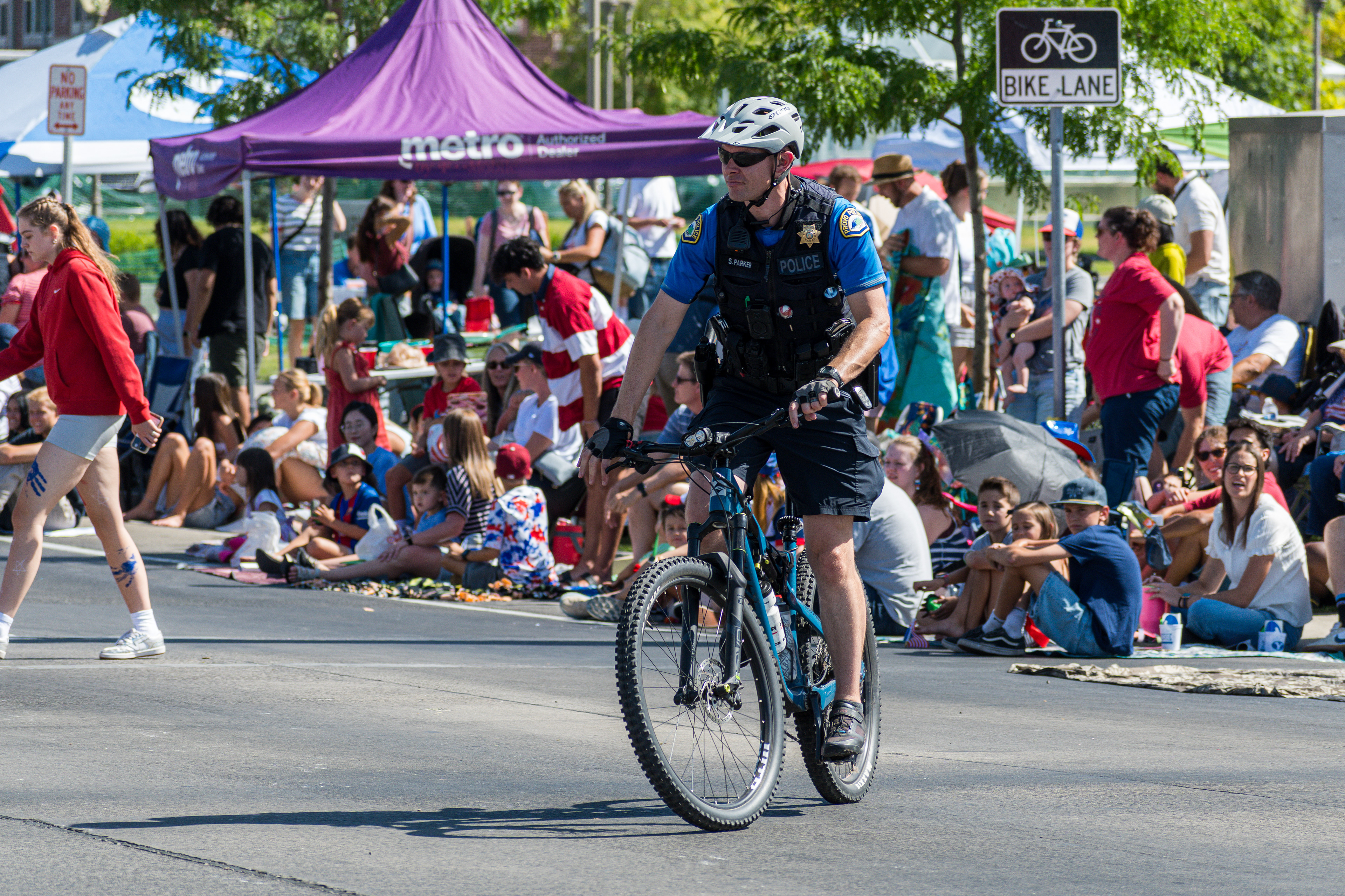 Provo, Utah – July 4, 2025: A police officer rides a bicycle along the parade route during the Freedom Festival Grand Parade, providing security and engaging with the community.