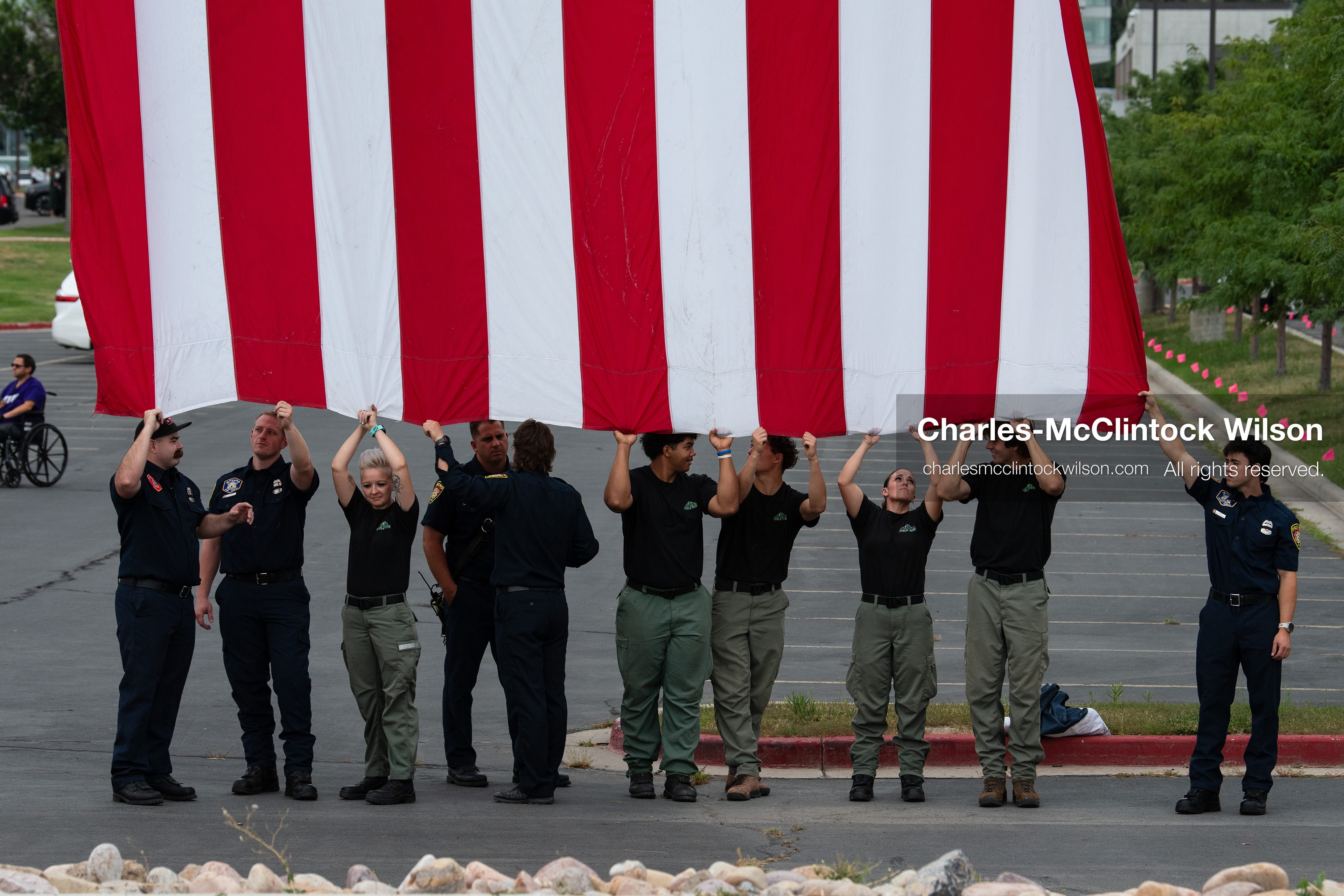 First responders stand in a row holding the bottom edge of a large American flag outside the UCCU Center at Utah Valley University in Orem, Utah, on Wednesday, July 29, 2026. More than 300 people came to the public memorial ceremony to honor Provo Fire Captain Spencer Long, his wife Katrina, and three of their sons, who died after a flash flood hit their campsite near the Sunglow Campground in Wayne County. (Photo by Charles-McClintock Wilson/Sipa USA)