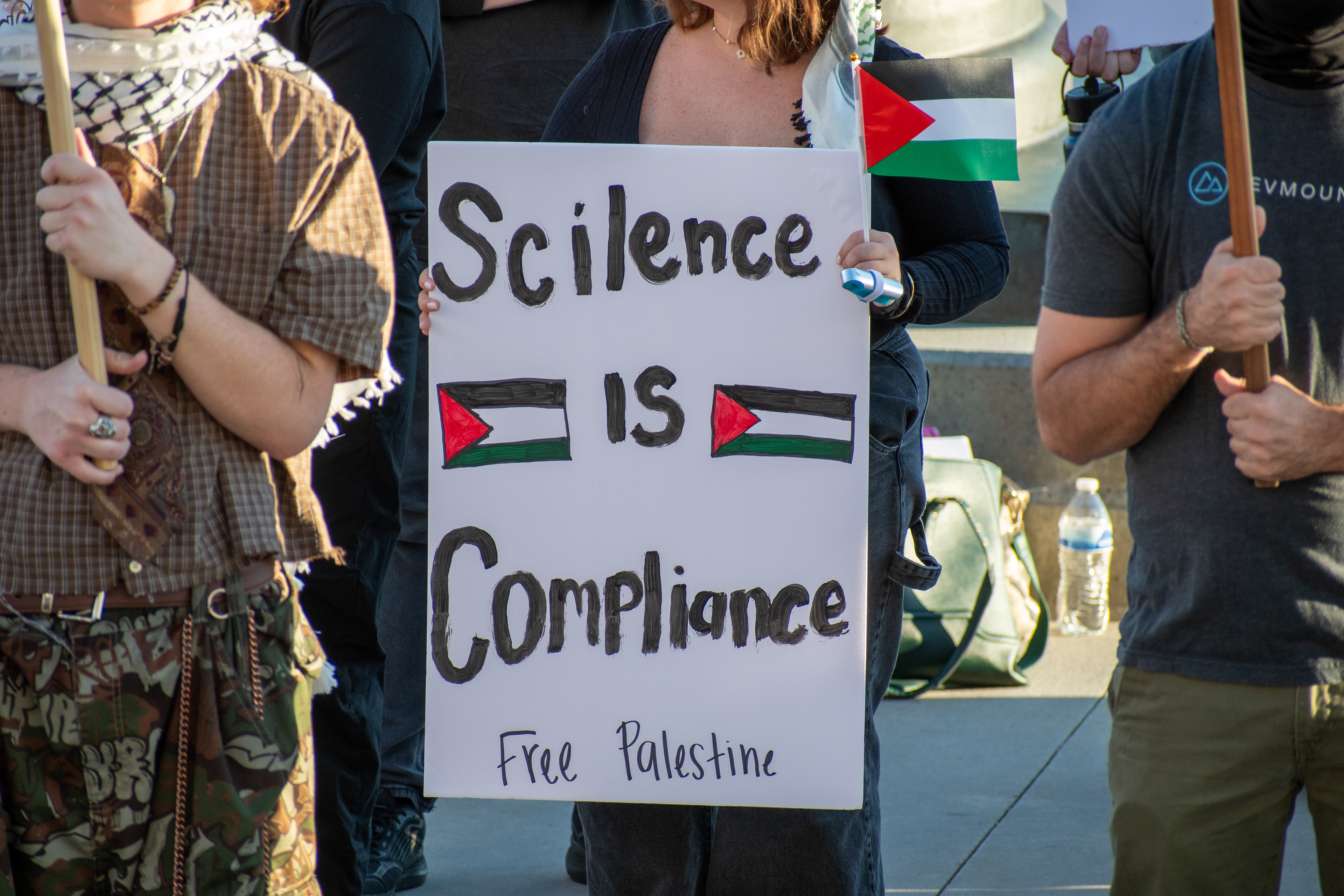  October 10, 2025, Salt Lake City, Utah, USA: A demonstrator holds a sign reading â€œScience is Compliance - Free Palestineâ€ during the Free Palestine Rally organized in front of the Utah State Capitol. Palestinian flags flank the message as participants gather in support of Palestinian rights. (Credit Image: © Charles-McClintock Wilson/ZUMA Press Wire)
