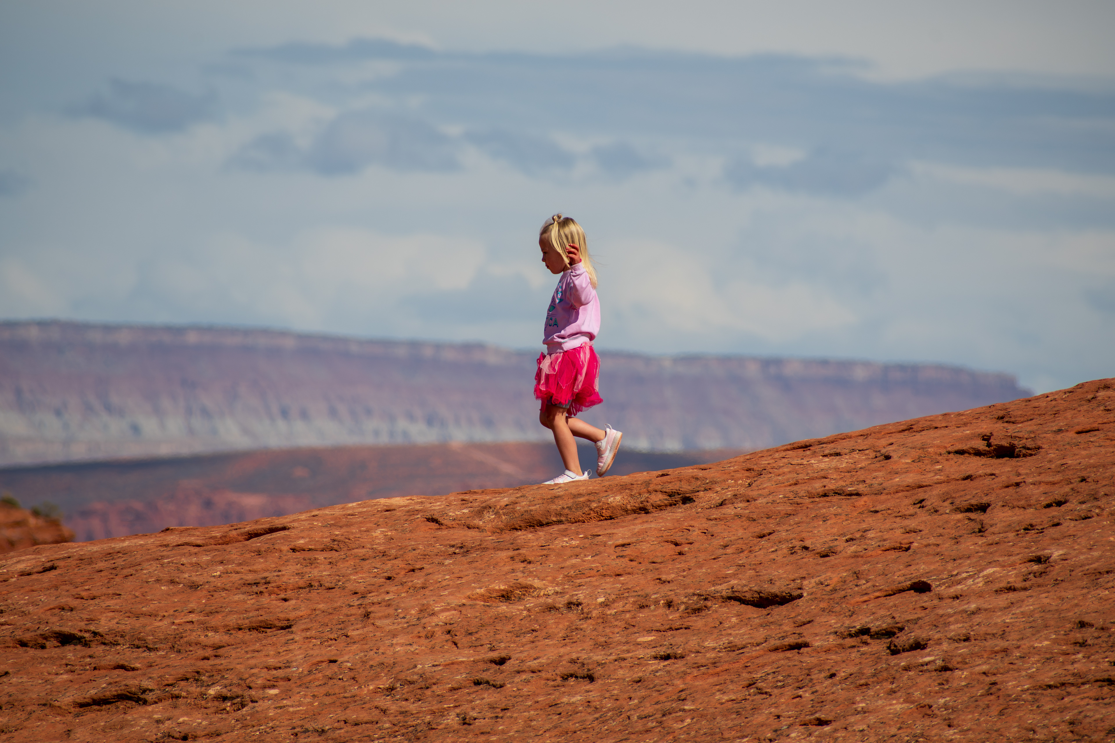 ST. GEORGE, UTAH, USA – MAY 5, 2025: A young girl walks on the sandstone rocks at Pioneer Park in St. George, Utah, surrounded by the natural beauty of the desert landscape.