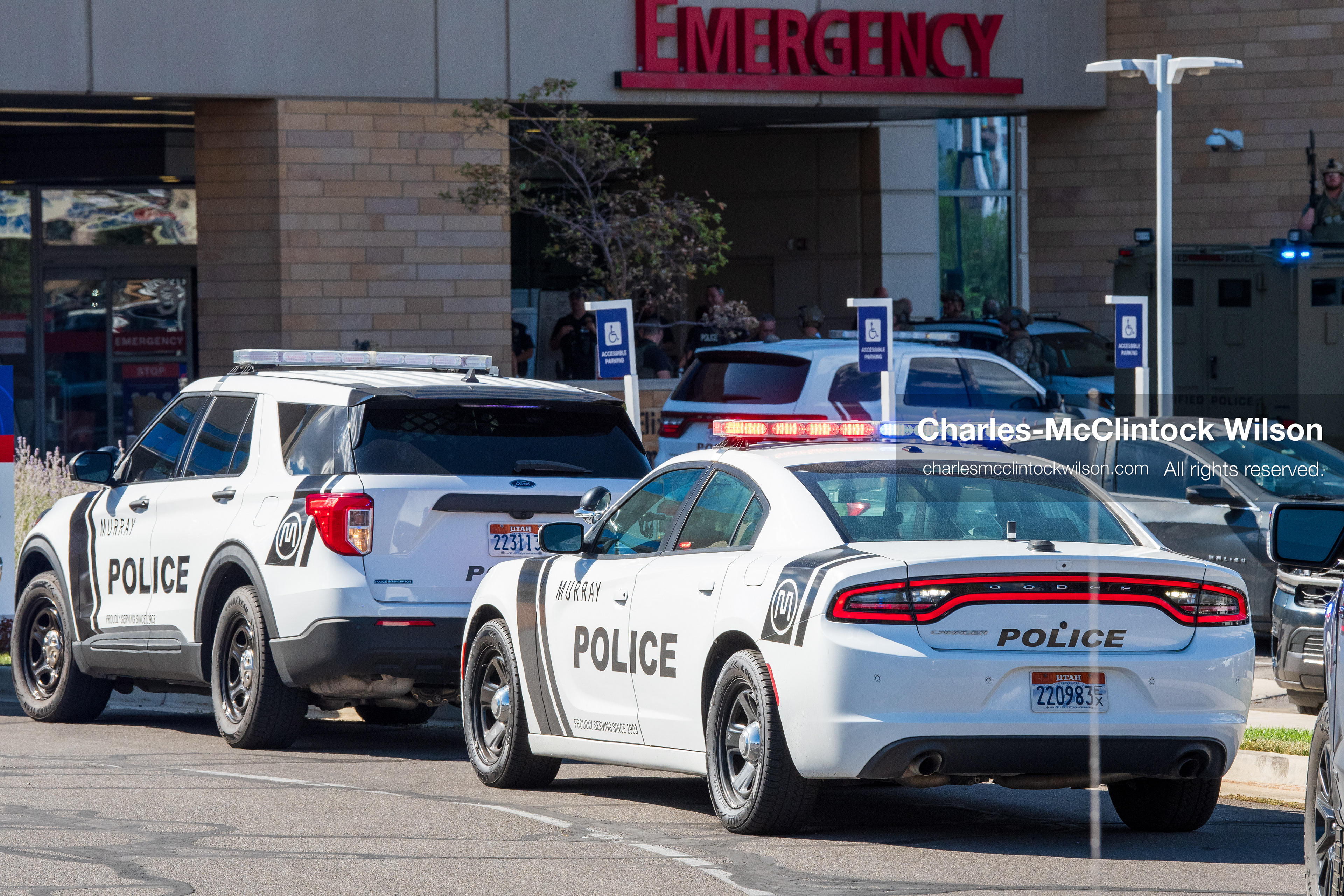 Marked police cruisers with emergency lights flashing sit parked in a line outside the emergency department entrance at Intermountain Medical Center in Murray, Utah, on Monday, August 17, 2026. Multiple regional law enforcement agencies converged to heavily secure the hospital perimeter as a safety precaution after shooting victims arrived from a fatal shootout that erupted outside a funeral service in nearby Kearns earlier that day. (Photo by Charles-McClintock Wilson/Sipa USA)