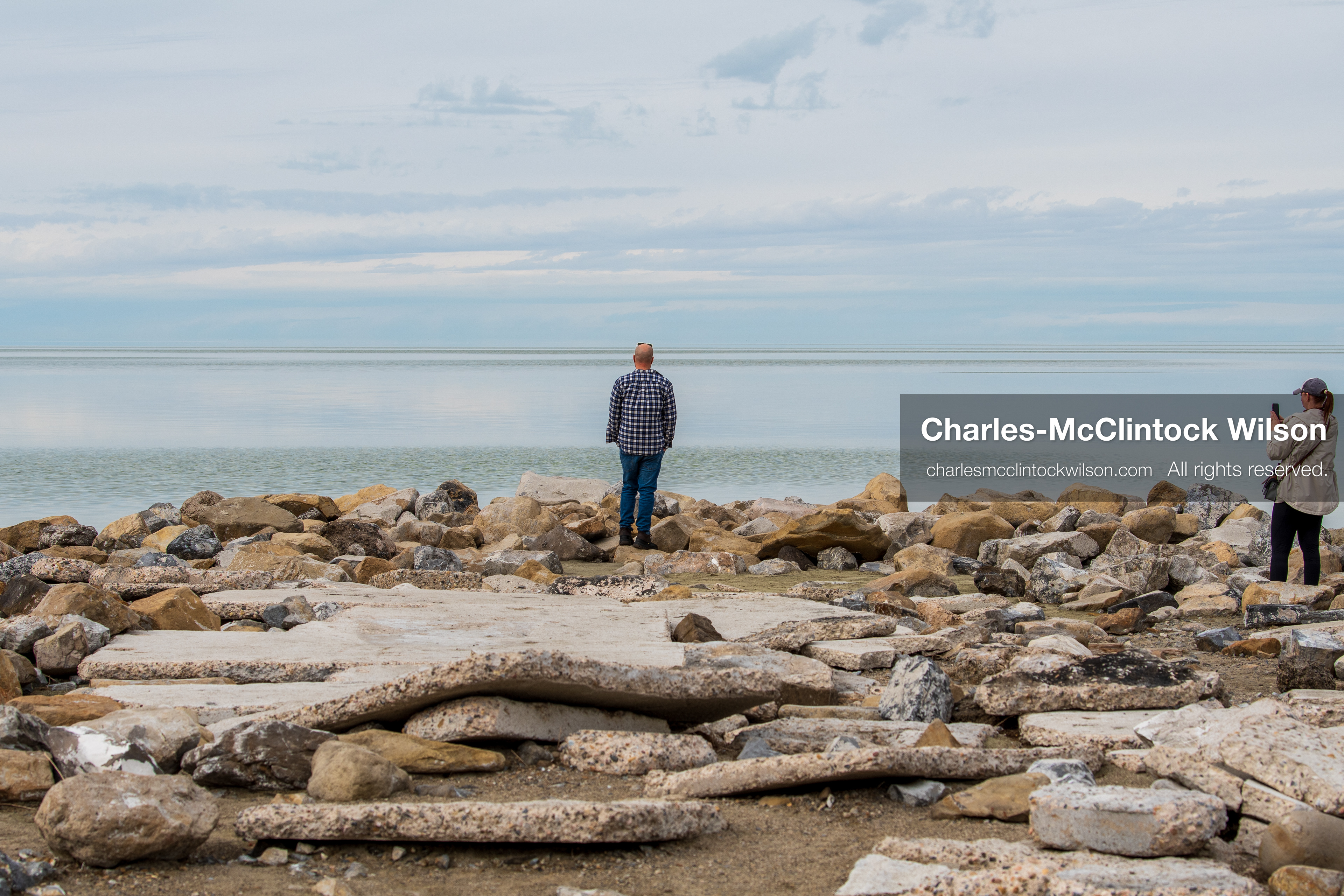 March 1, 2026, Great Salt Lake, Utah, USA: Two people stand along a rocky shoreline at the Great Salt Lake as water levels in the region remain historically low. Reports from state officials and the Great Salt Lake Strike Team state that the lake continues to fall within a serious adverse‑effects range, with elevations among the lowest recorded in more than one hundred years. The lake has drawn increased public attention as lawmakers consider large‑scale water projects and long‑term plans to address declining conditions. (Credit Image: © Charles‑McClintock Wilson/ZUMA Press Wire)