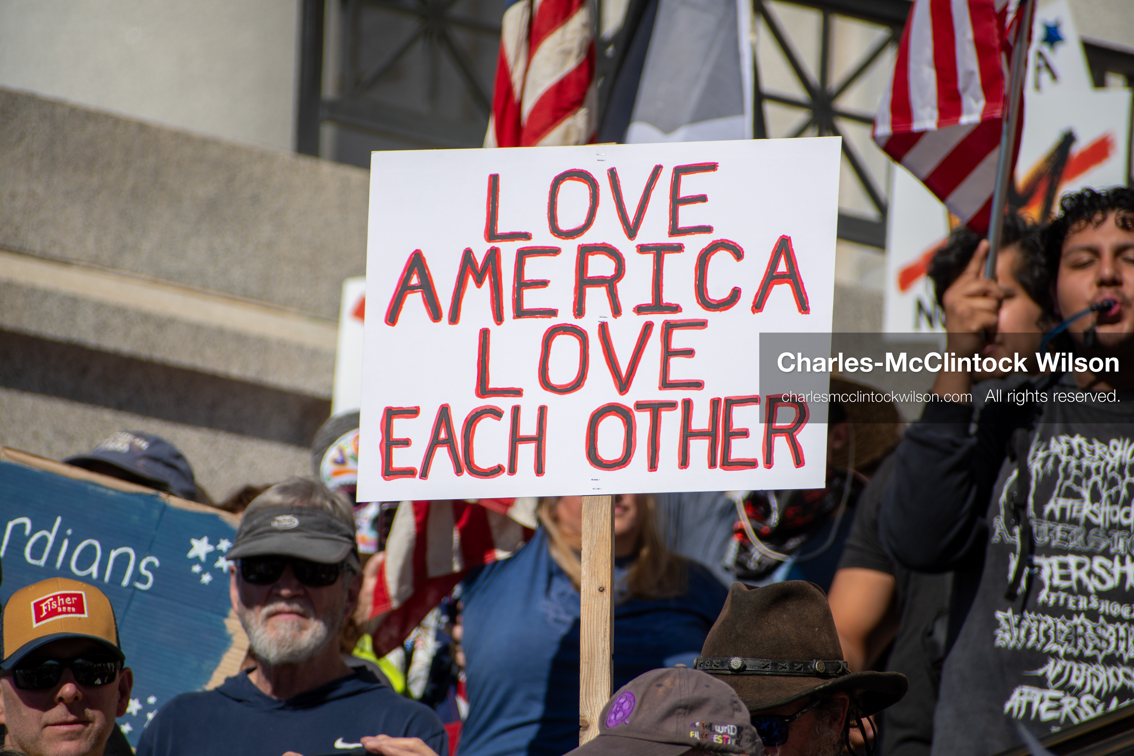October 18, 2025, Salt Lake City, Utah, USA: A demonstrator raises a placard during a "No Kings" protest held at the Utah State Capitol. Other participants and signs are visible in the background during the public gathering.