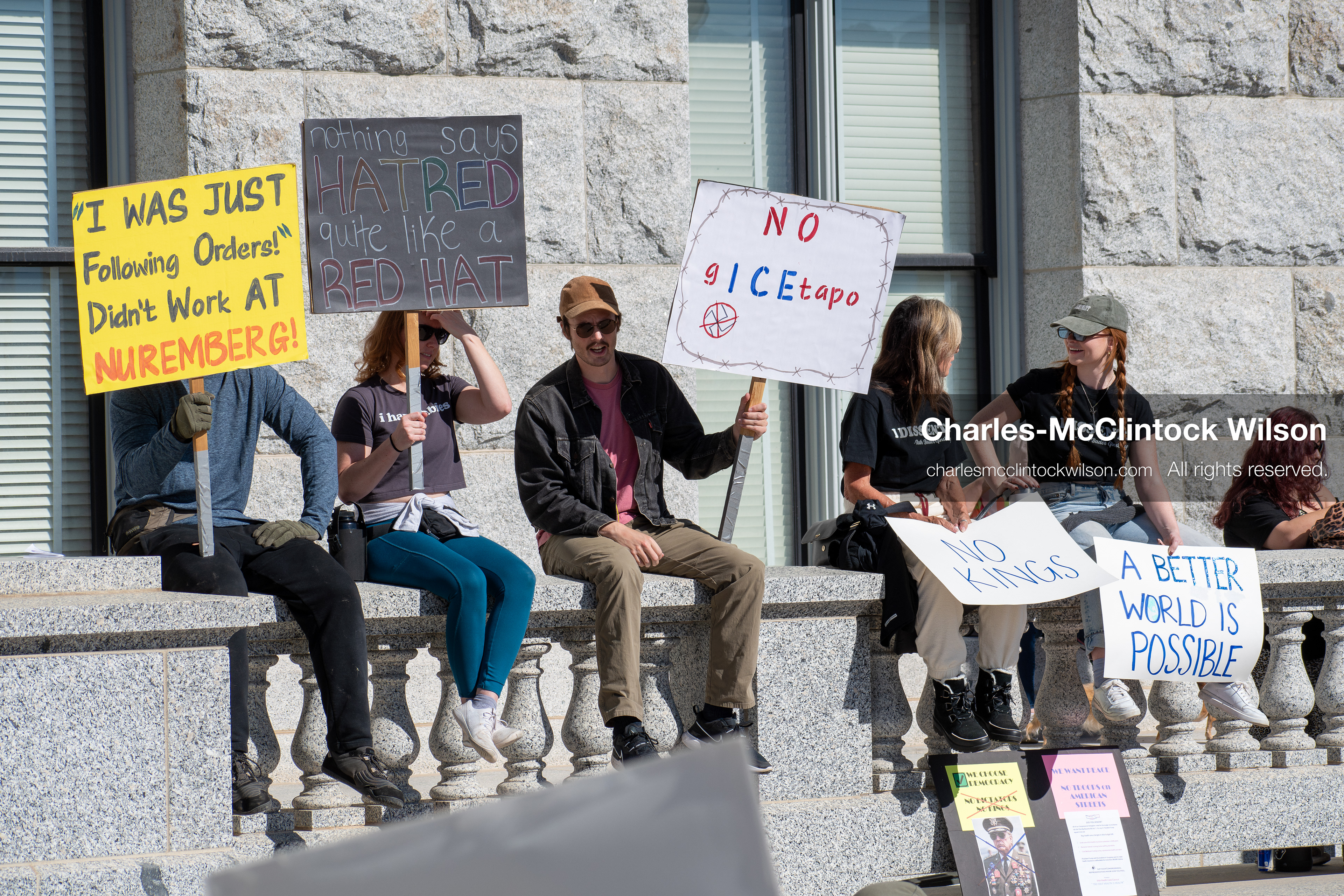 October 18, 2025, Salt Lake City, Utah, USA: Demonstrators sit on a stone ledge during a "No Kings" protest at the Utah State Capitol. The protest was part of a nationwide mobilization.