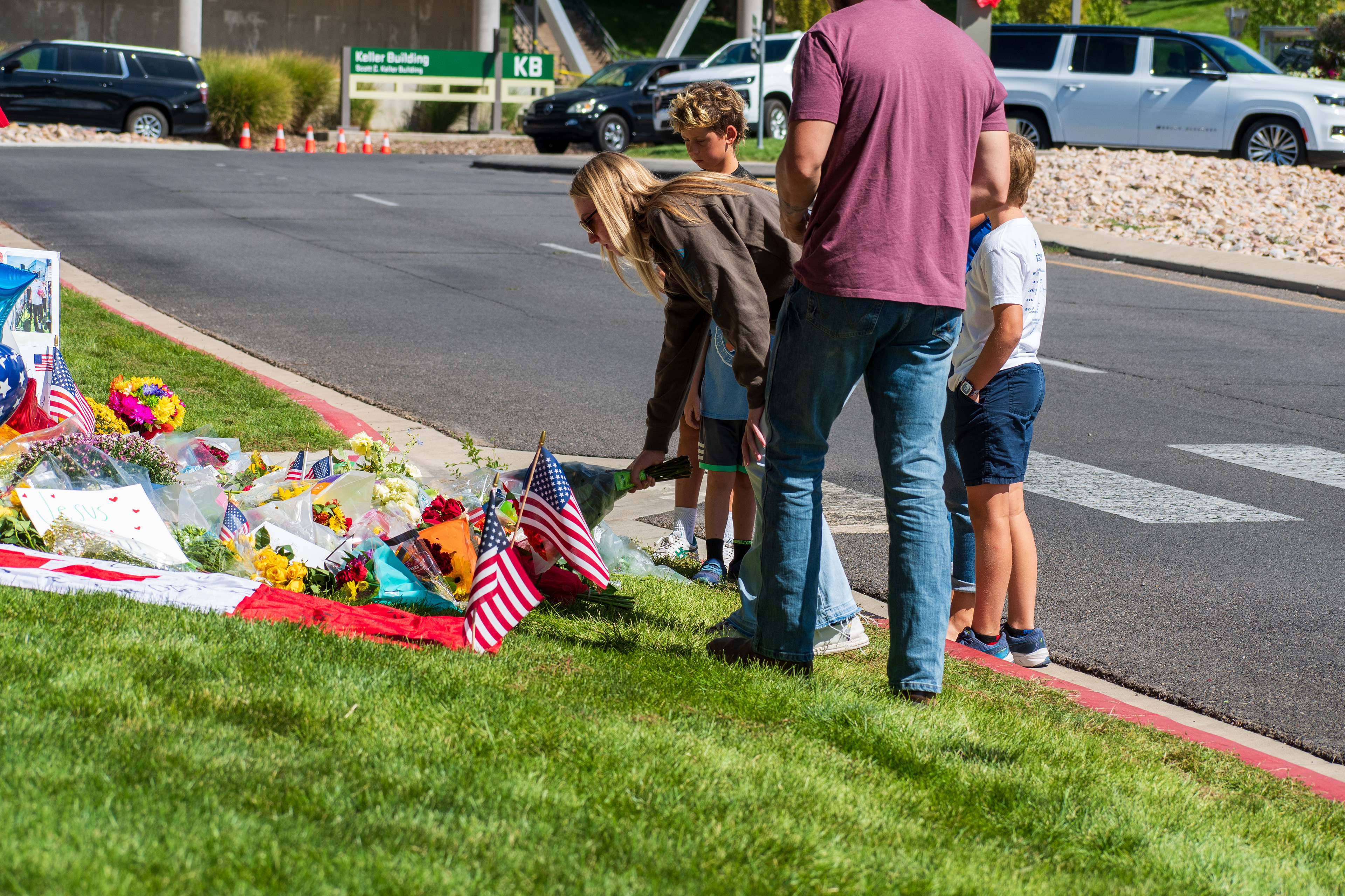 OREM, UTAH – SEPTEMBER 12, 2025: Families gather at a memorial site for Charlie Kirk on the campus of Utah Valley University. The tribute includes American flags, balloons, flowers, and handwritten posters arranged near a building entrance. © Charles‑McClintock Wilson / ZUMA Press