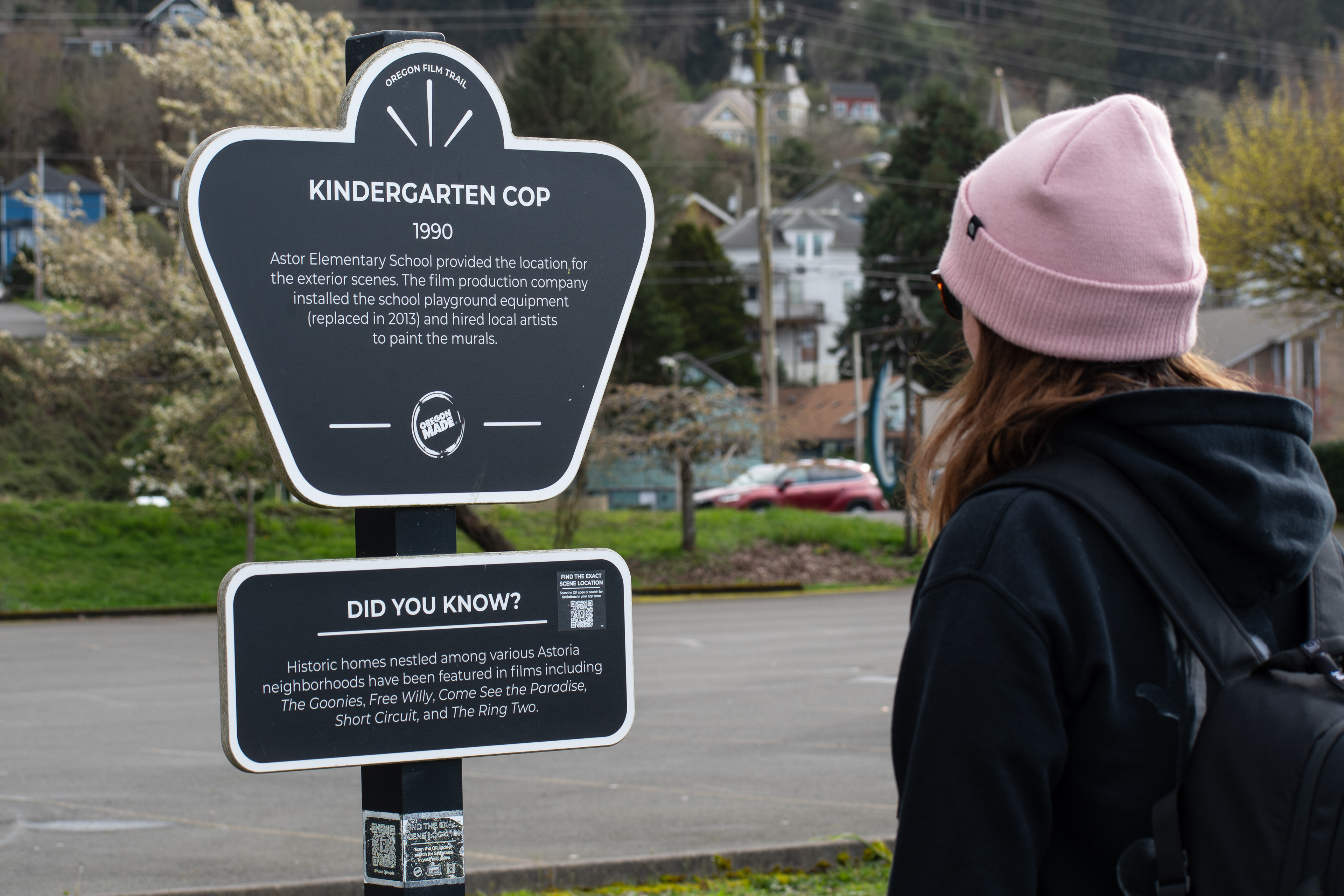 Astoria, Oregon, USA - April 10, 2025: A woman reads the Kindergarten Cop filming location sign on the Oregon Film Trail, marking the 1990 film's connection to Astoria.