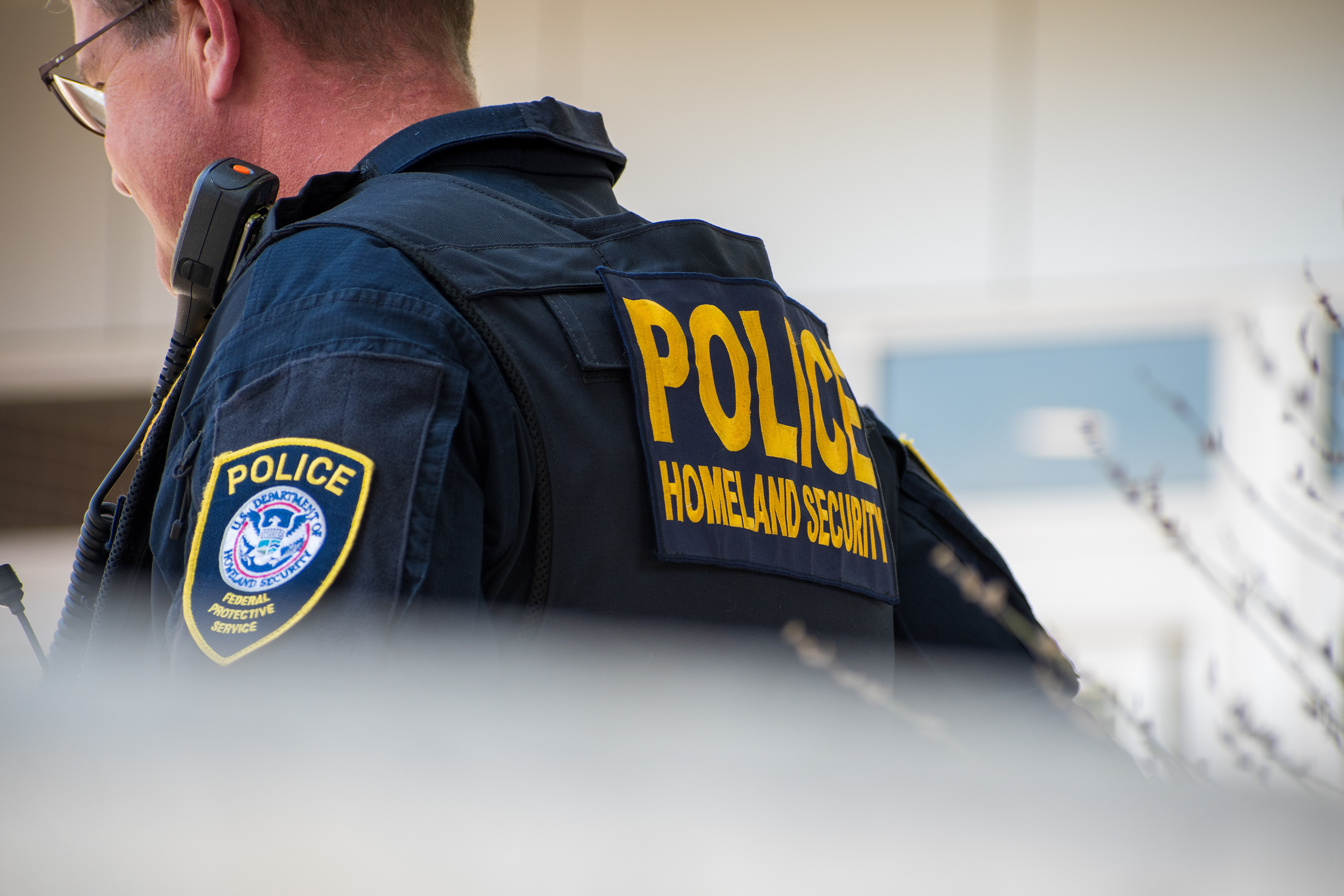 A Homeland Security police officer stands outside the Utah Valley Convention Center during the DHS Career Expo in Provo, Utah, on September 15, 2025. The tactical vest, marked “POLICE HOMELAND SECURITY,” reflects the agency’s visible perimeter presence as federal recruitment efforts intensified under expanded national security initiatives. Photograph by Charles‑McClintock Wilson / ZUMA Press Wire