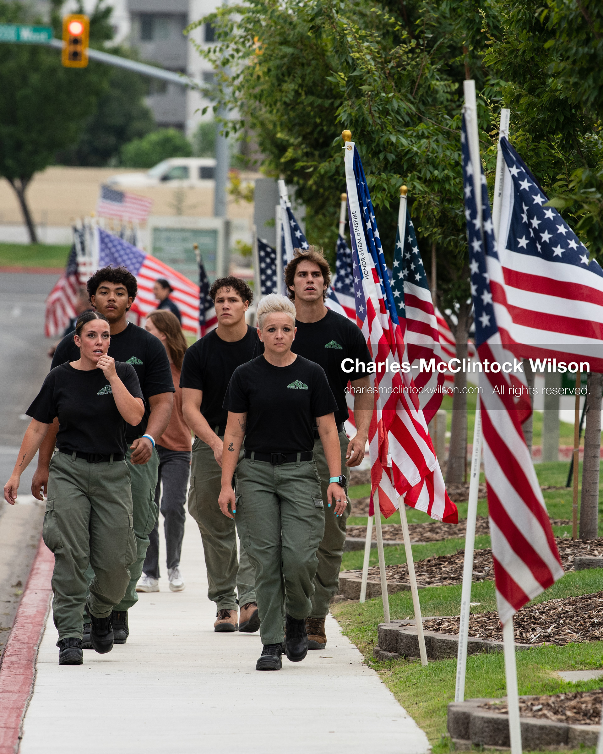 A group of volunteers walks down a flag-lined sidewalk outside the UCCU Center at Utah Valley University in Orem, Utah, on Wednesday, July 29, 2026. More than 300 people came to the public memorial ceremony to honor Provo Fire Captain Spencer Long, his wife Katrina, and three of their sons, who died after a flash flood hit their campsite near the Sunglow Campground in Wayne County. (Photo by Charles-McClintock Wilson/Sipa USA)