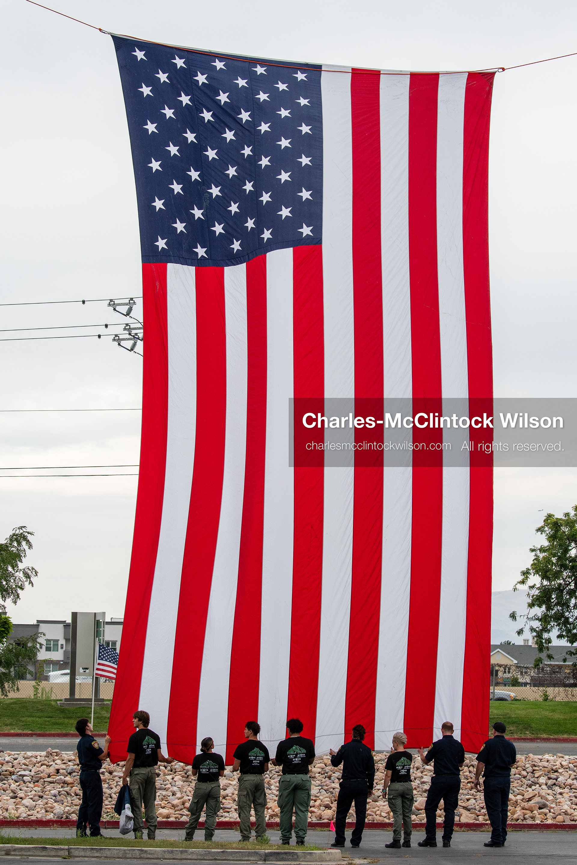 A group of first responders hangs a large American flag vertically outside the UCCU Center at Utah Valley University in Orem, Utah, on Wednesday, July 29, 2026. More than 300 people came to the public memorial ceremony to honor Provo Fire Captain Spencer Long, his wife Katrina, and three of their sons, who died after a flash flood hit their campsite near the Sunglow Campground in Wayne County. (Photo by Charles-McClintock Wilson/Sipa USA)