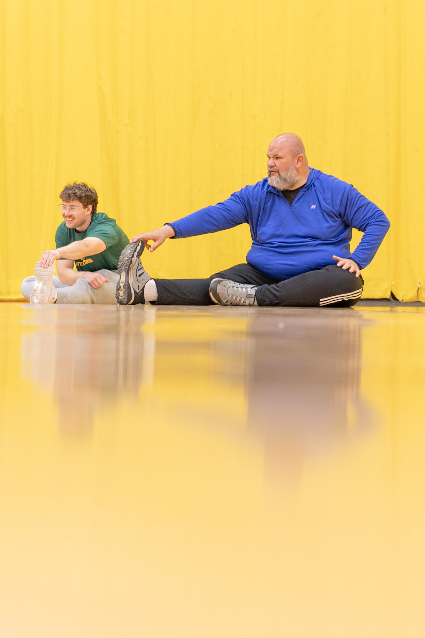 Brendan Paterson and Dan Entress stretch before powerlifting practice at Brockport University on April 17, 2025. Brendan mentors Dan, who is training for a Special Olympics powerlifting tournament.