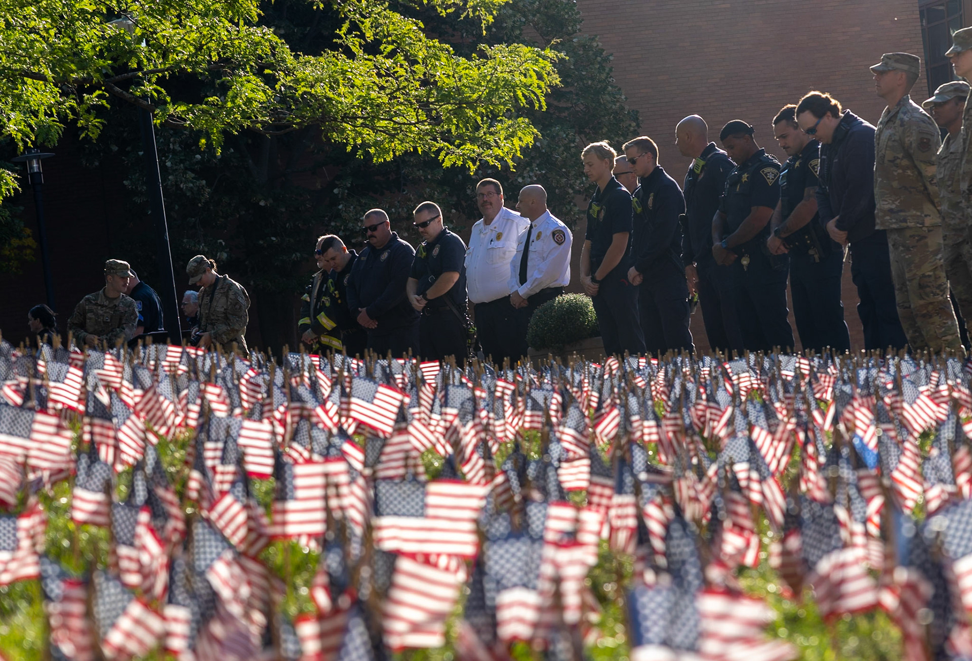 First responders and military personnel gather around a field of American flags during a moment of silence at Rochester Institute of Technology’s 9/11 remembrance ceremony as they paid their respects to the lives lost in the attacks on the World Trade Center in New York City.