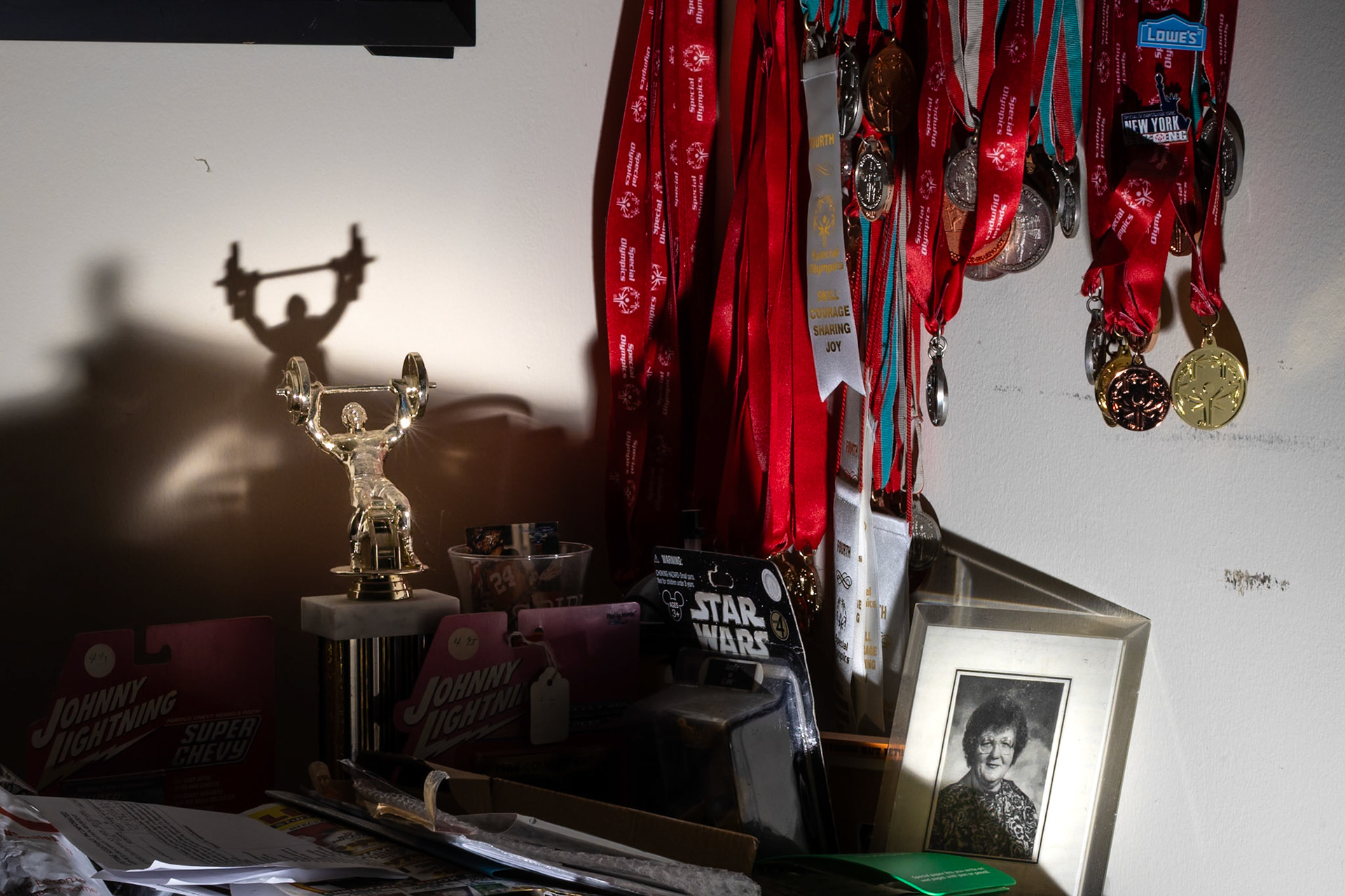 Dan Entress’s living room shelf at his apartment in Greece, NY on December 9, 2025 features dozens of medals he’s won in Special Olympics sports competitions and a photograph of his mother, Grace.