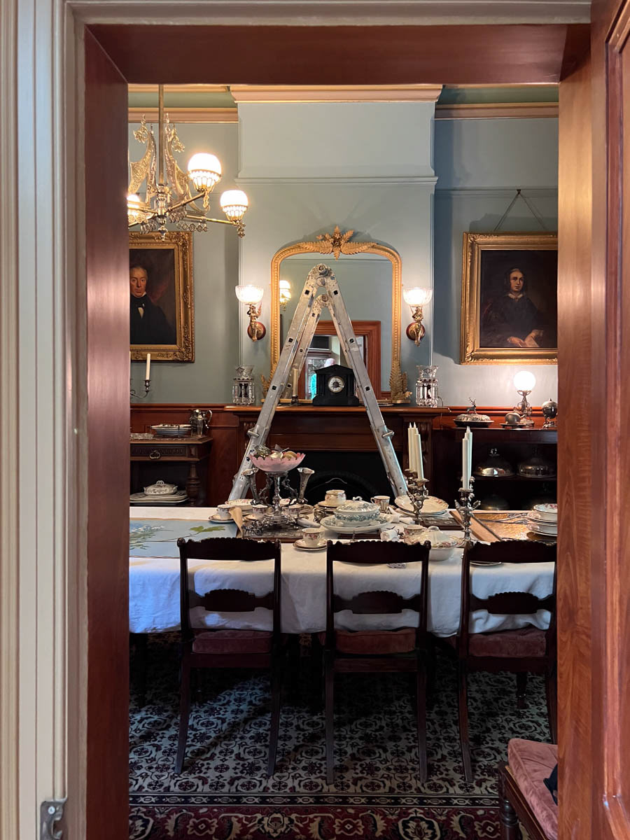 The room is fully furnished, the sideboards are filled with vases.