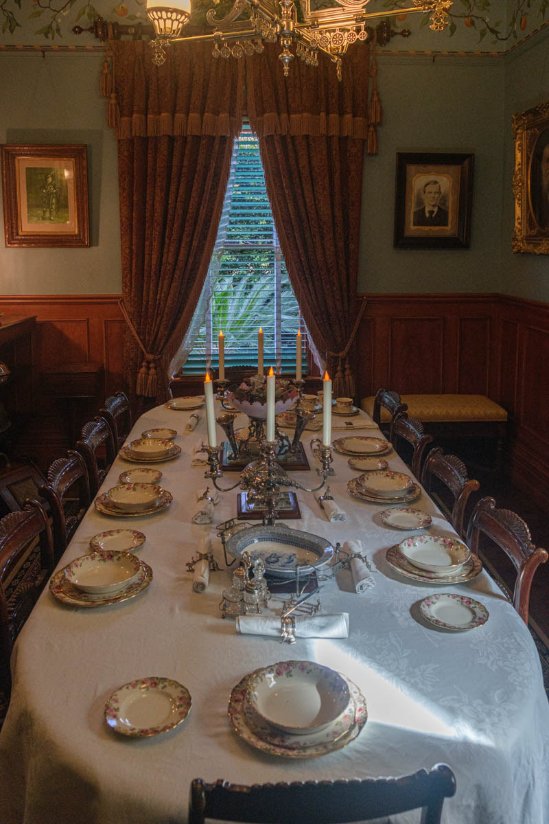 A sumptuous table is set, discretely lit by a central chandelier and sconces on either side of the mirror installed on the fireplace.