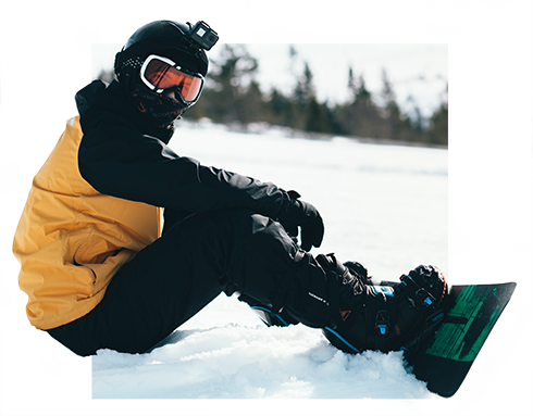 snowboarder sitting on the snow. they image has been cropped so that parts of the snowboarder extend beyond the square frame and appear to break out of the box.