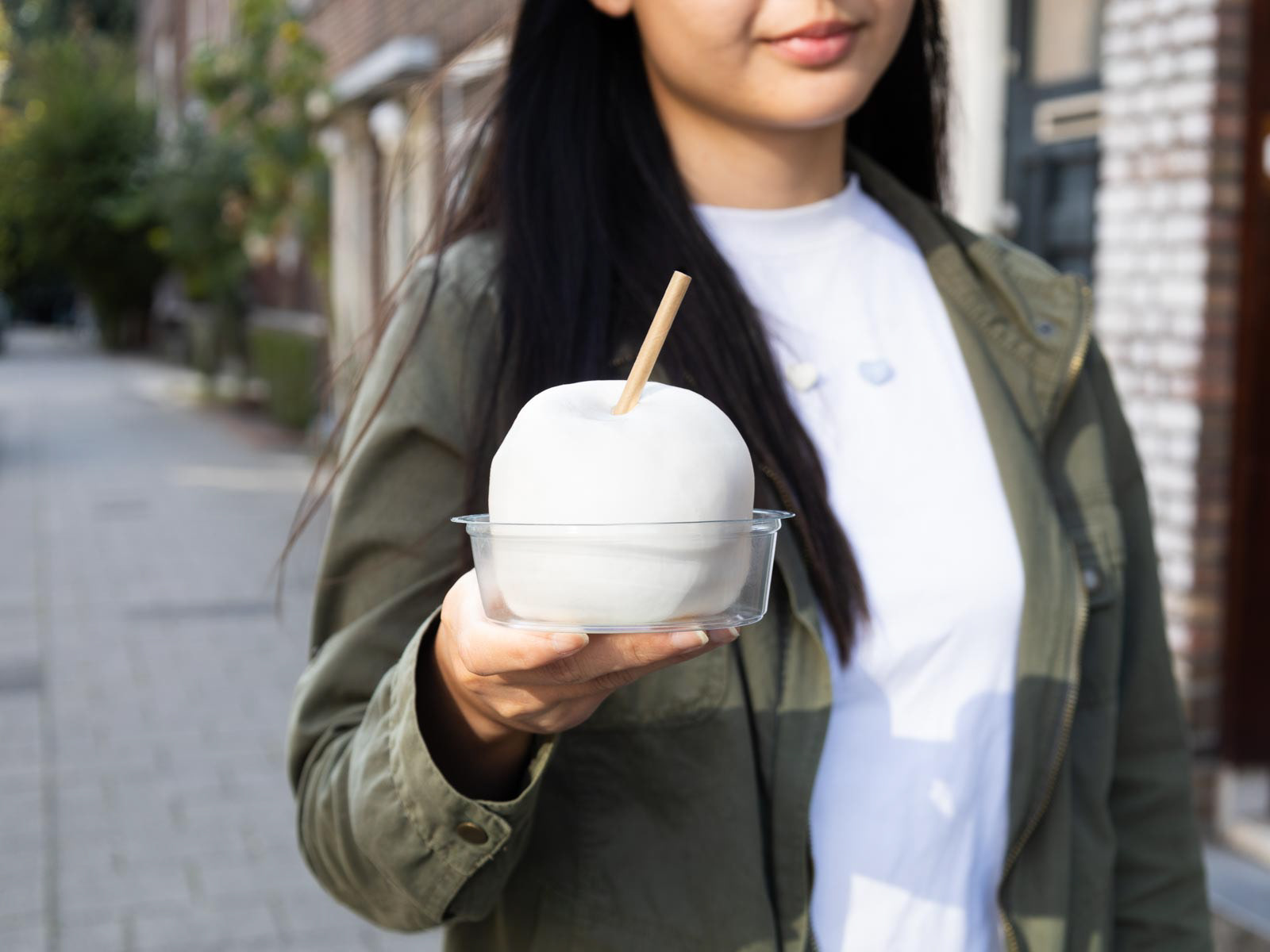 A girl holding a coconut snow ball with takeaway packaging, shot by a Dutch food photographer.