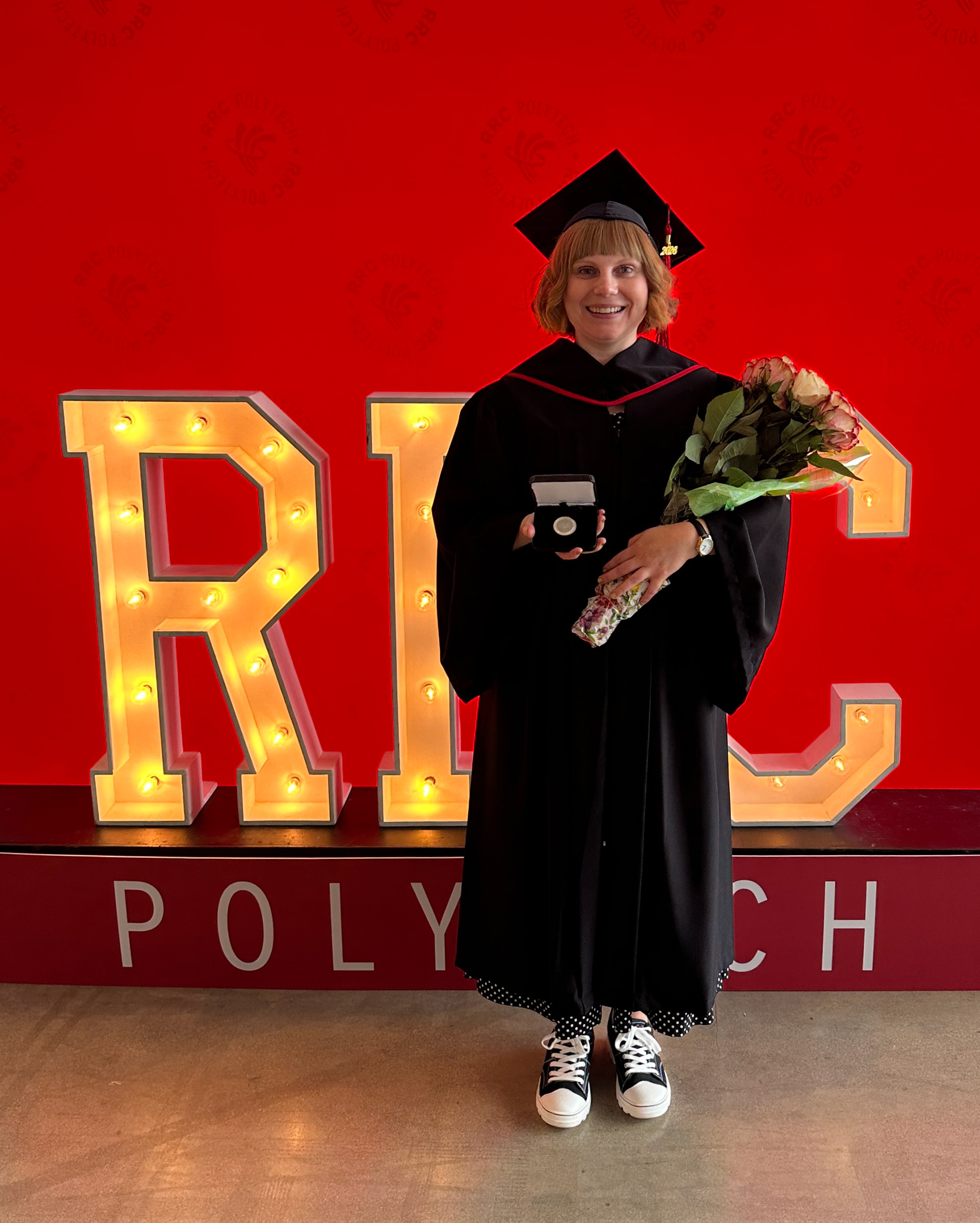 Mandi holding her LG Medal at her graduation.