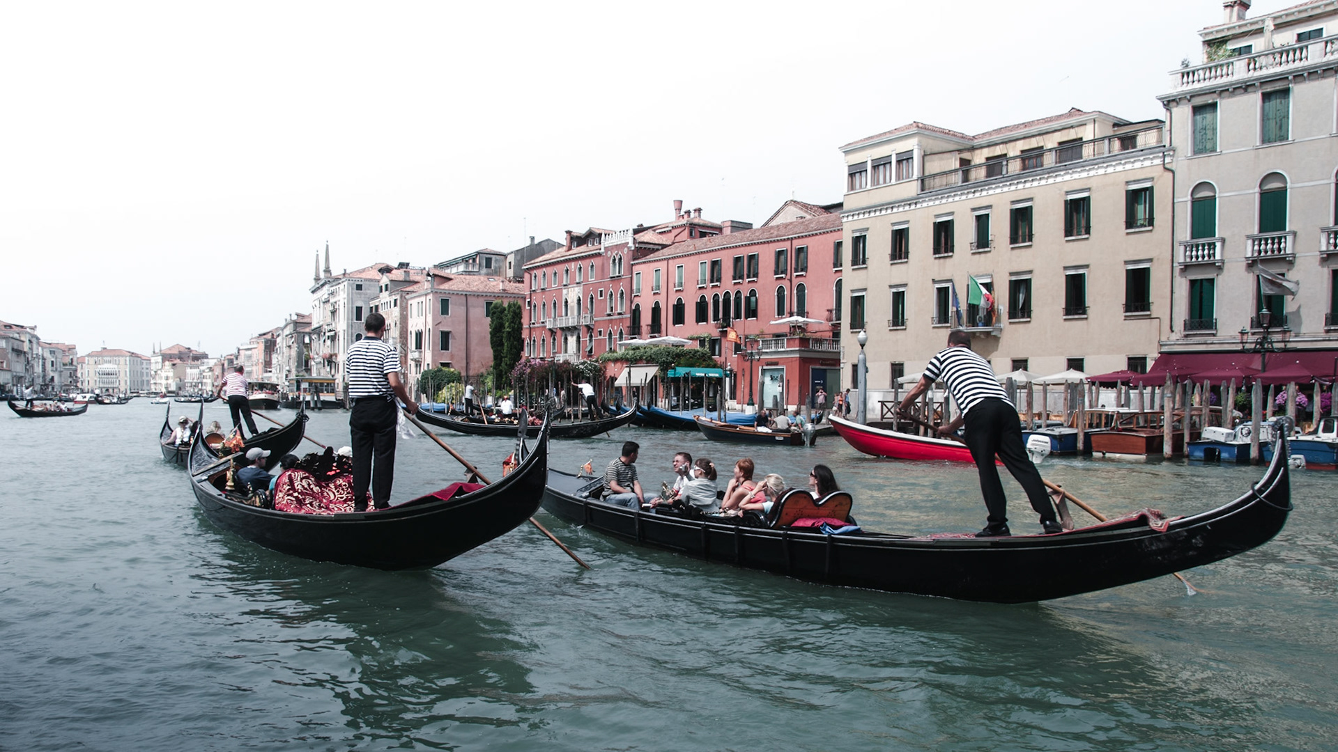 Two gondoliers carry tourists in their gondolas along the Canal Grande.