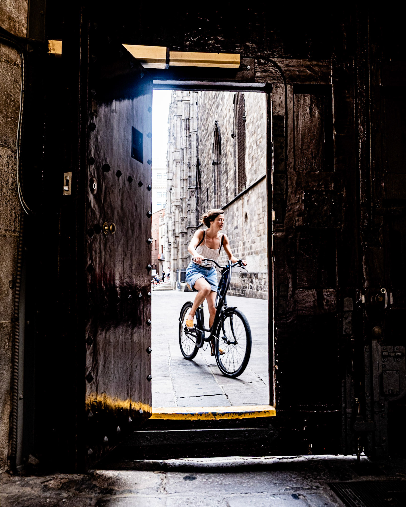 A woman rides a bike in front of the Casa de l'Ardiaca in the Gothic Quarter in Barcelona