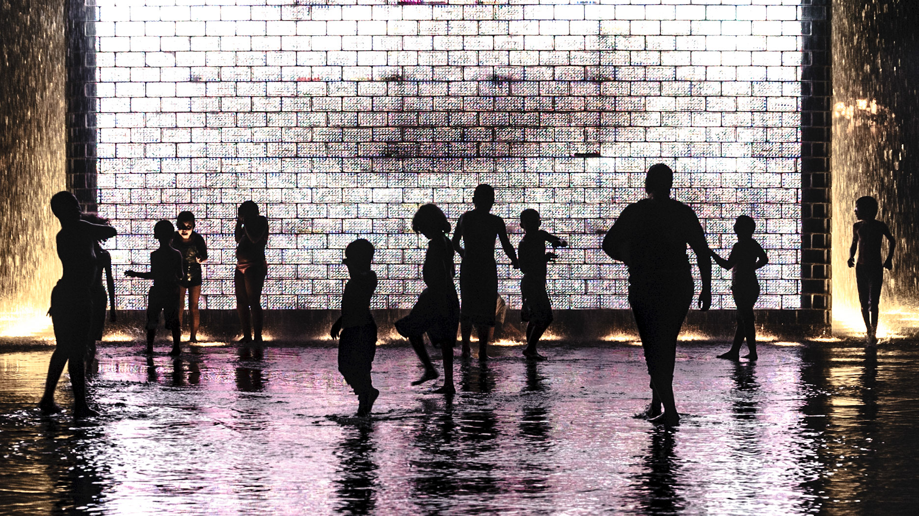 Kids cool down in Millenium Park Water Fall late at night after another 100F heat wave struck Mid-West in 2011.