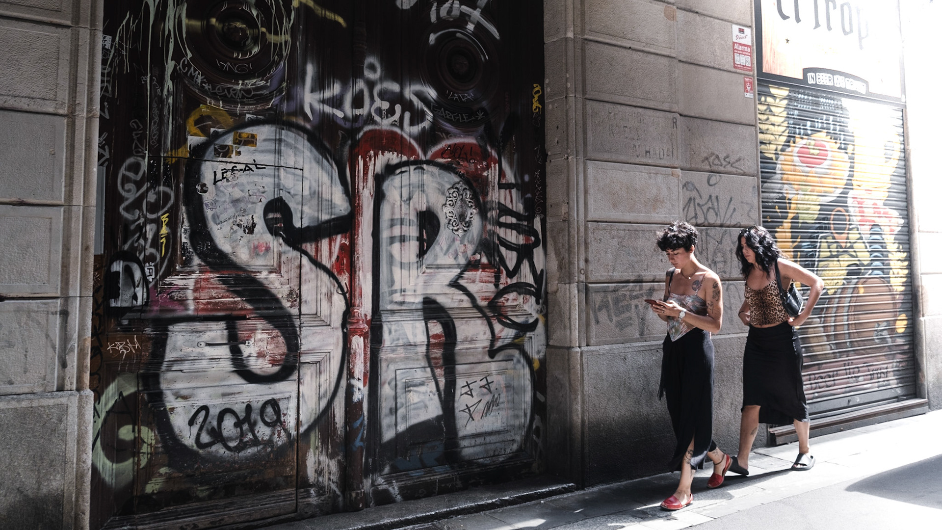 Pedestrians walk past the graffiti covered historical building in Gothic Quaraters in Barcelona