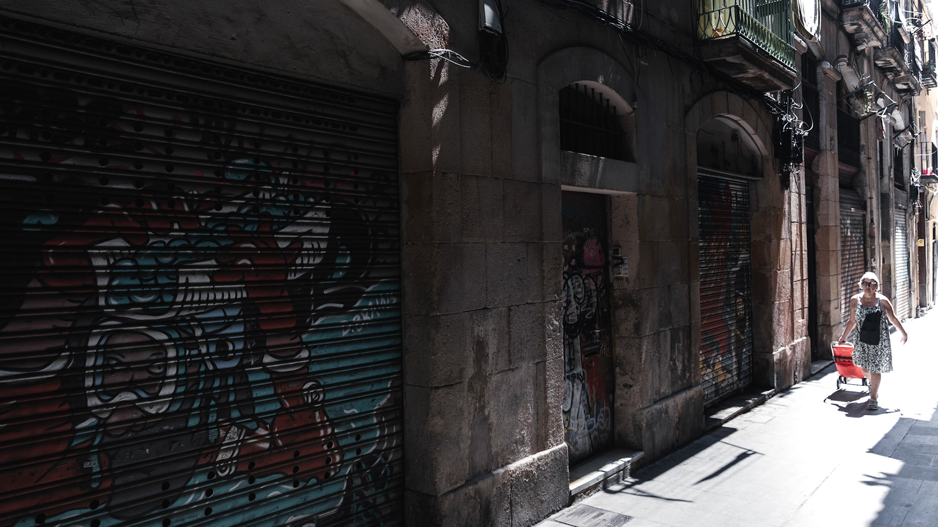 A neighborhood resident carries groceries home on Carrer de Sant Pere Més Alt street in Barcelona