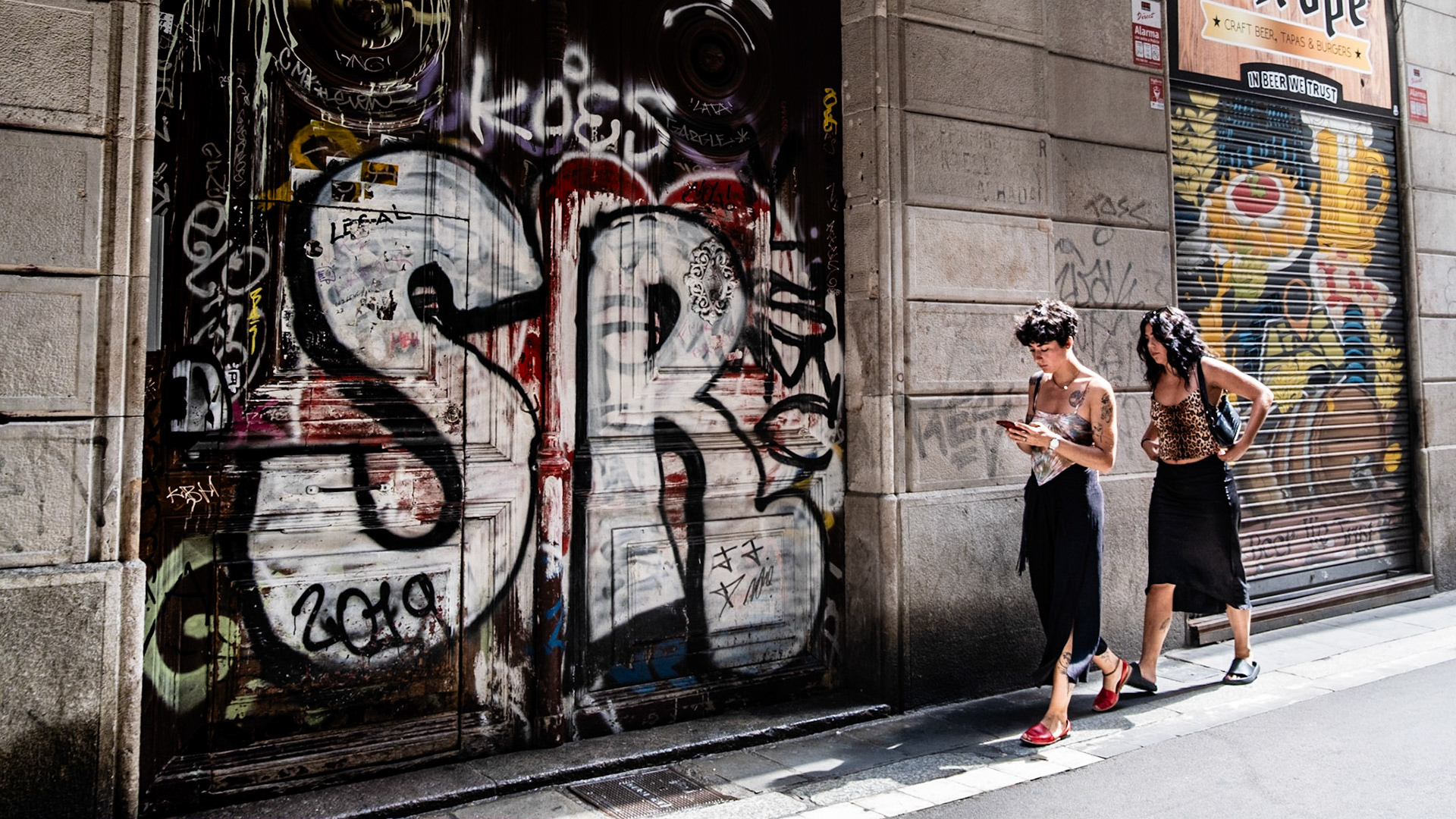 Pedestrians walk past the graffiti covered historical building in Gothic Quaraters in Barcelona