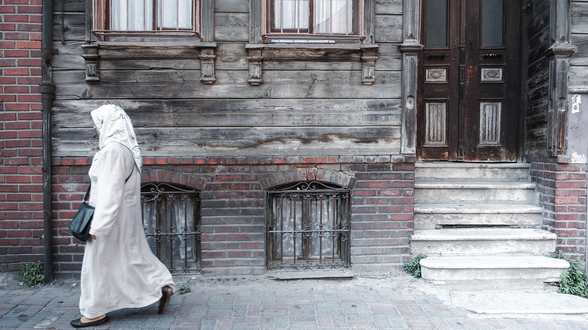A woman passes by an old historical house, typical of this area. The government plans to demolish entire sections of this neighborhood and replace them with modern (and expensive) housing projects.