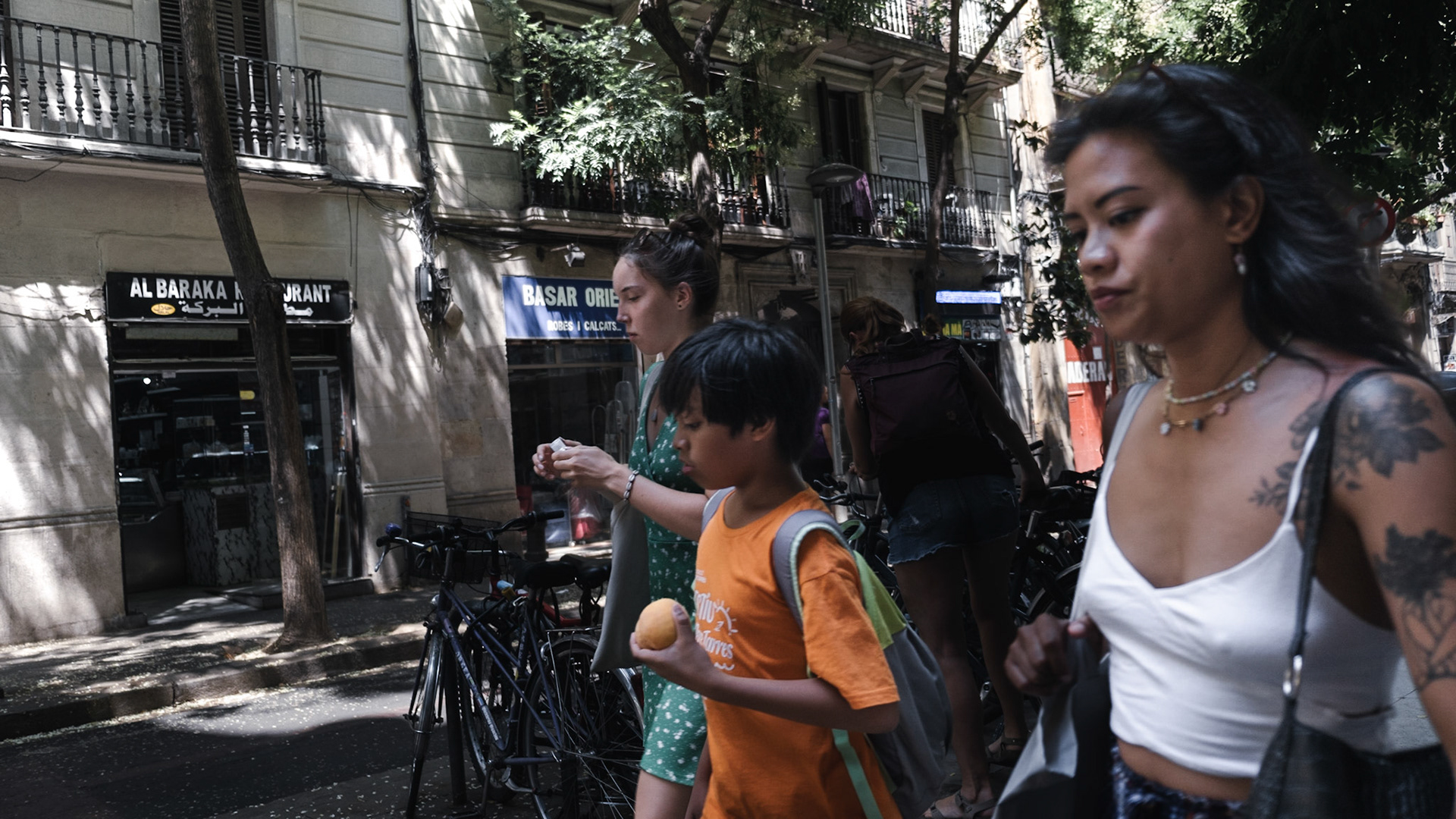 A family walks by on a quiet street of El Raval district in Barcelona