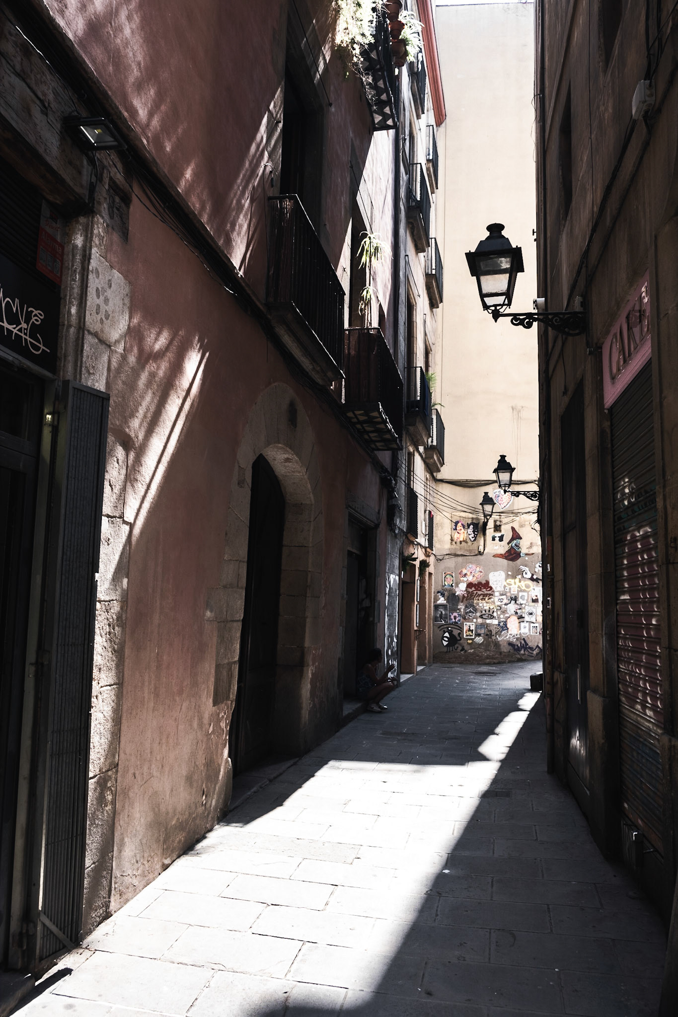 A woman takes a cigarette break in an arrow alley in El Born district of Barcelona
