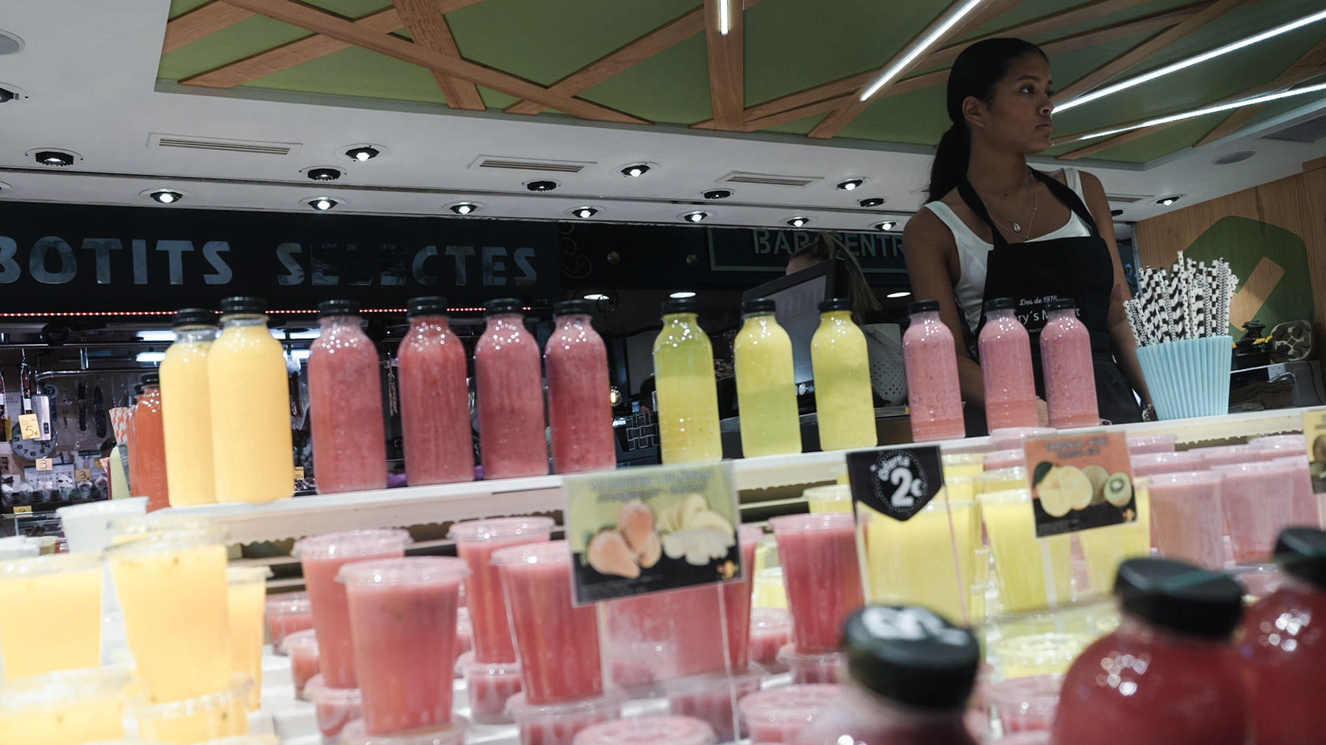 A woman sells a variety of freshly squeezed juices in the La Boqueria Market in La Rambla Barcelona
