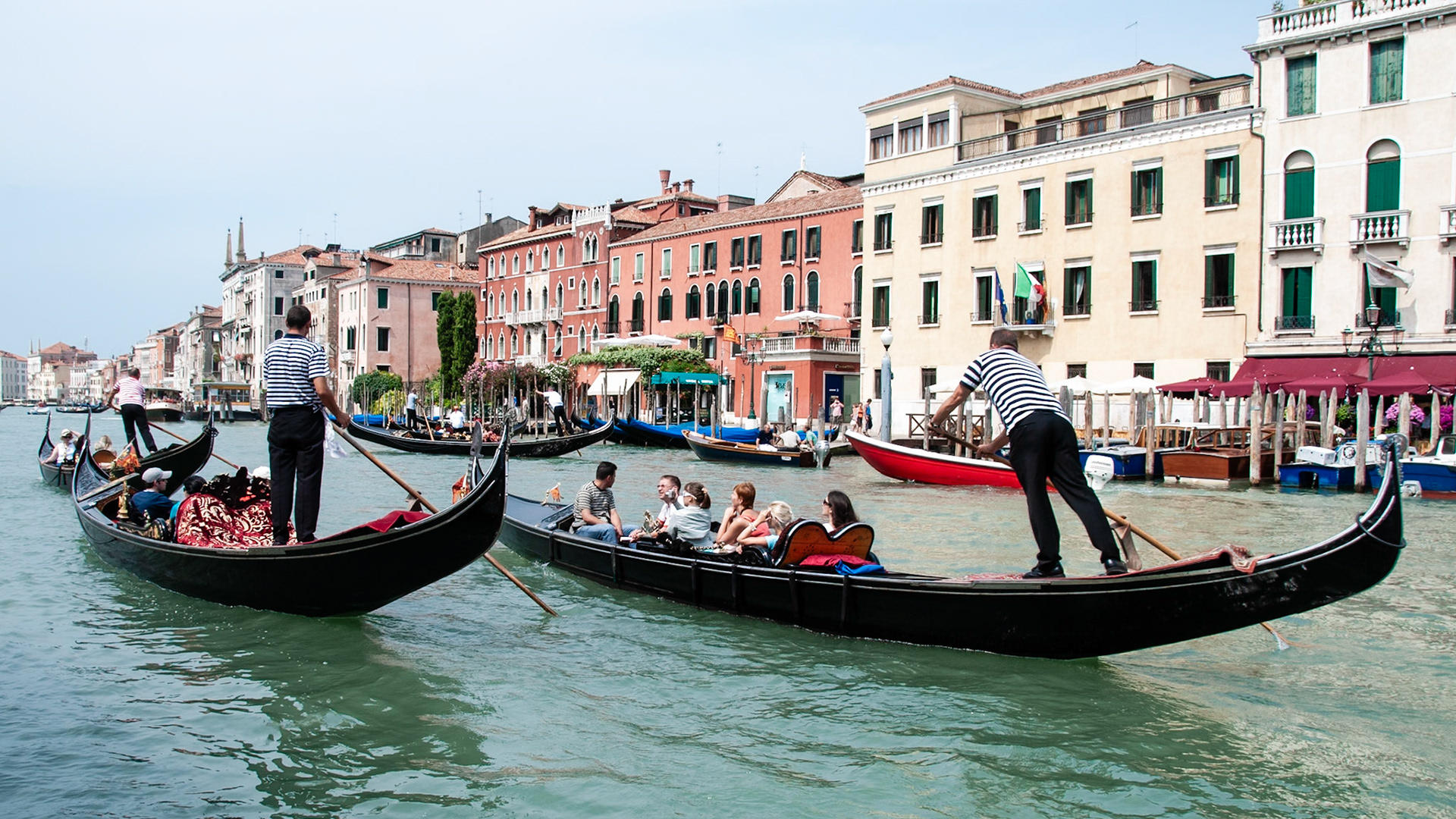 Two gondoliers carry tourists in their gondolas along the Canal Grande.