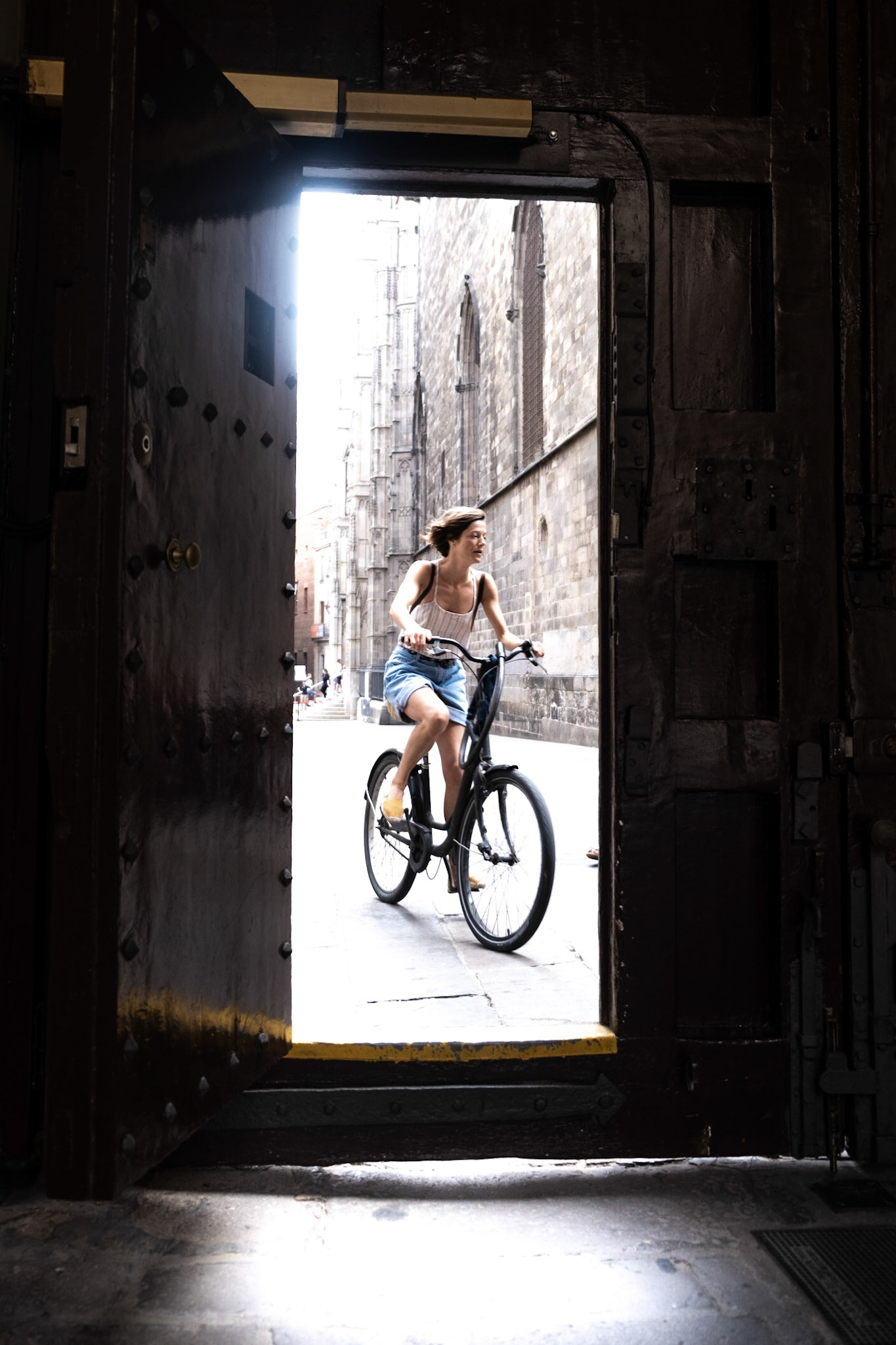 A woman rides a bike in front of the Casa de l'Ardiaca in the Gothic Quarter in Barcelona