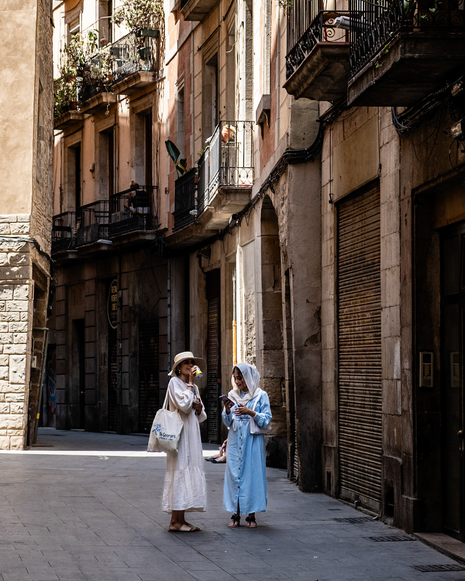 Two women in white stand on Via Laietana that separates Gothic Quarters from El Born districts in Barcelona