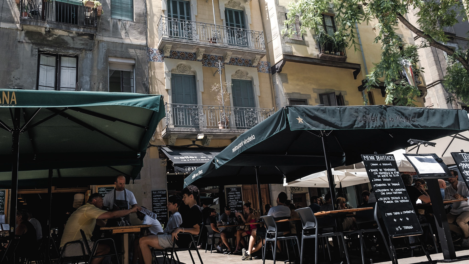 Tourists enjoy food in an outdoor restaurant during busy lunch hour in a historic district of El Born in Barcelona
