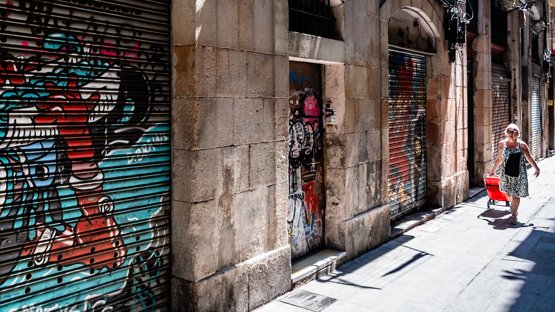 A neighborhood resident carries groceries home on Carrer de Sant Pere Més Alt street in Barcelona