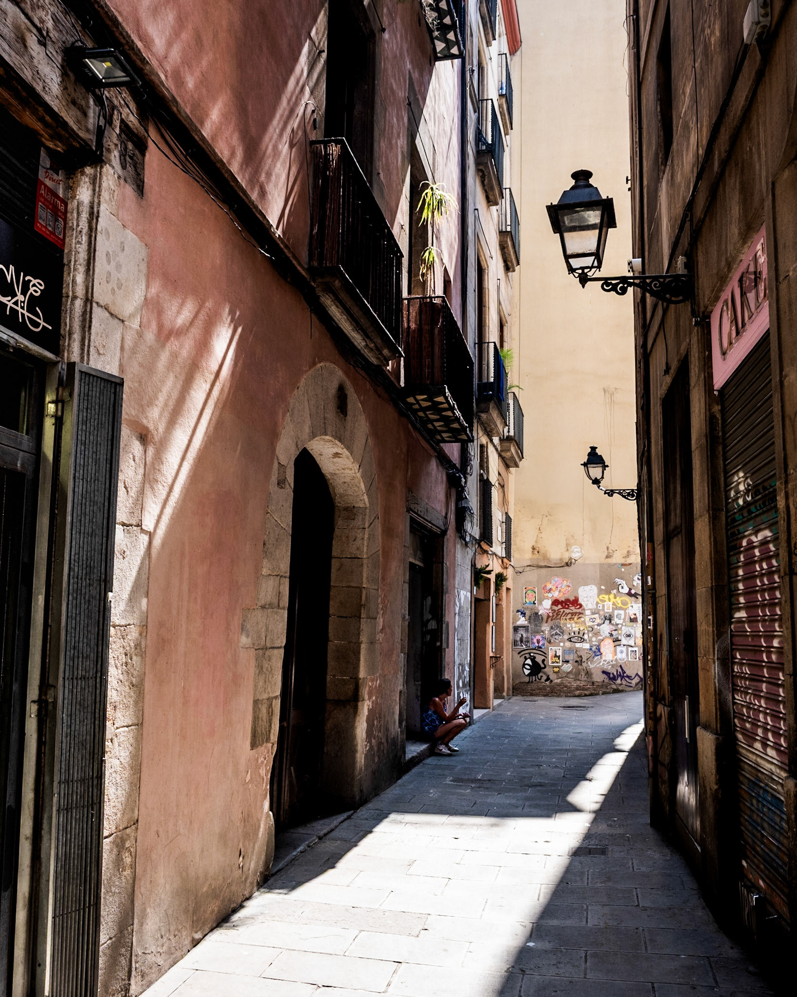 A woman takes a cigarette break in an arrow alley in El Born district of Barcelona