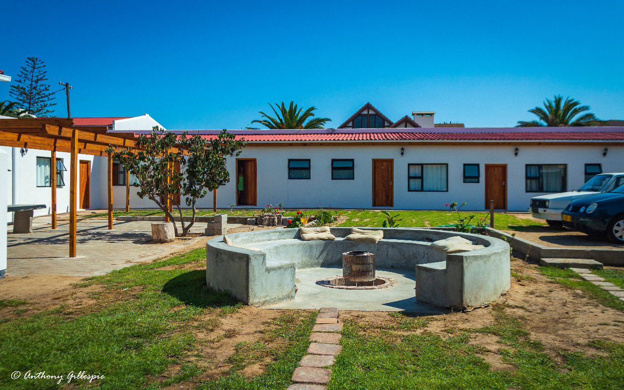 A front view of the Roman Fire Pit, courtyard, rooms and parking area of Beach garden Accomodation.