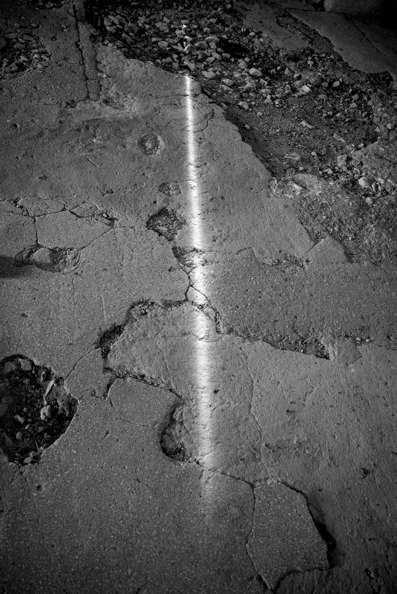 Interior of Camp 65. May 22, 2025. A crack in the wall of a hut lets a faint ray of sunlight in.