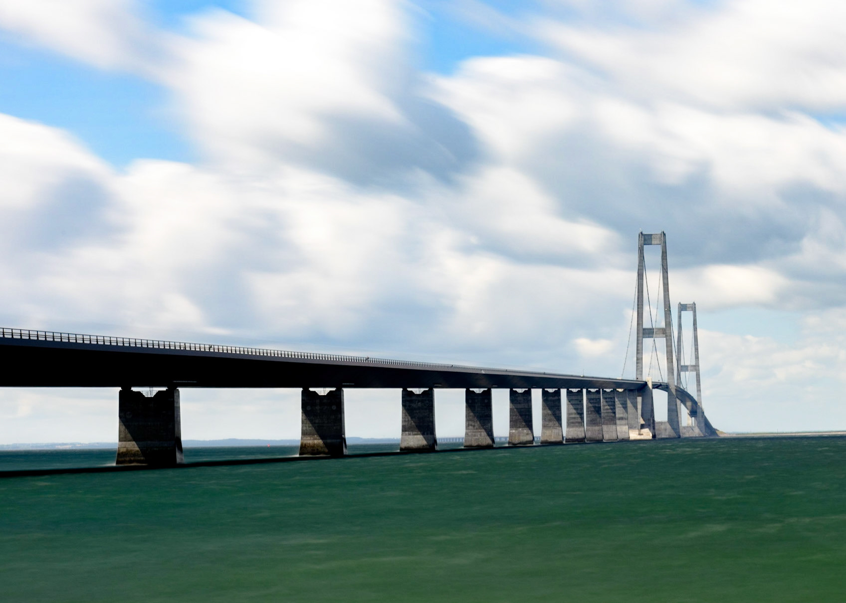 The Great Belt Fixed link (Danish: Storebæltsforbindelsen) is a multi-element fixed link crossing the Great Belt strait between the Danish islands of Zealand and Funen. It consists of five structures: a road suspension bridge and a railway tunnel between Zealand and the small island Sprogø located in the middle of the Great Belt, and a box girder bridge for both road and rail traffic between Sprogø and Funen. The "Great Belt Bridge" (Danish: Storebæltsbroen) commonly refers to the suspension bridge, although it may also be used to mean the box-girder bridge or the link in its entirety. The suspension bridge, officially known as the East Bridge, has the world's third longest main span (1.6 km), and the longest outside of Asia. It was designed by the Danish engineering firms COWI and Ramboll.